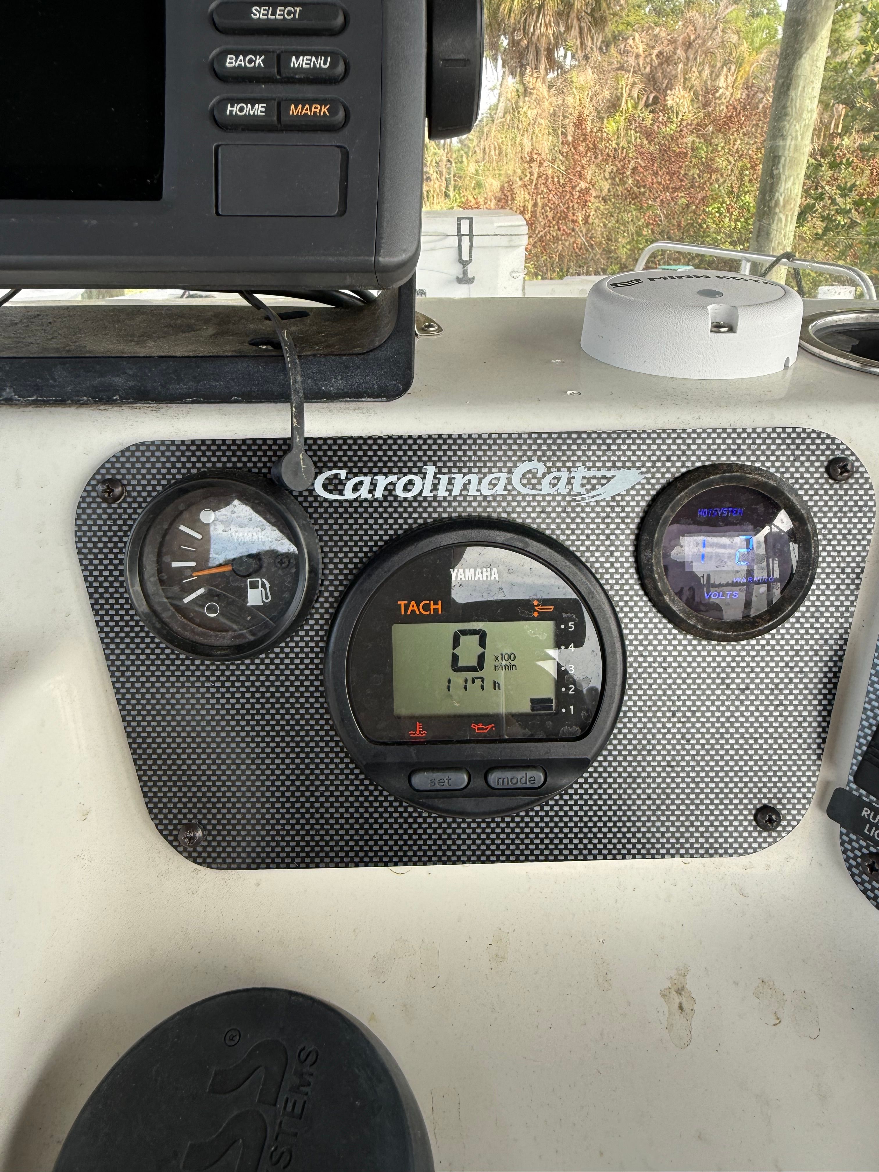Dashboard of a Carolina Cat 18CC boat with tachometer and fuel gauge.