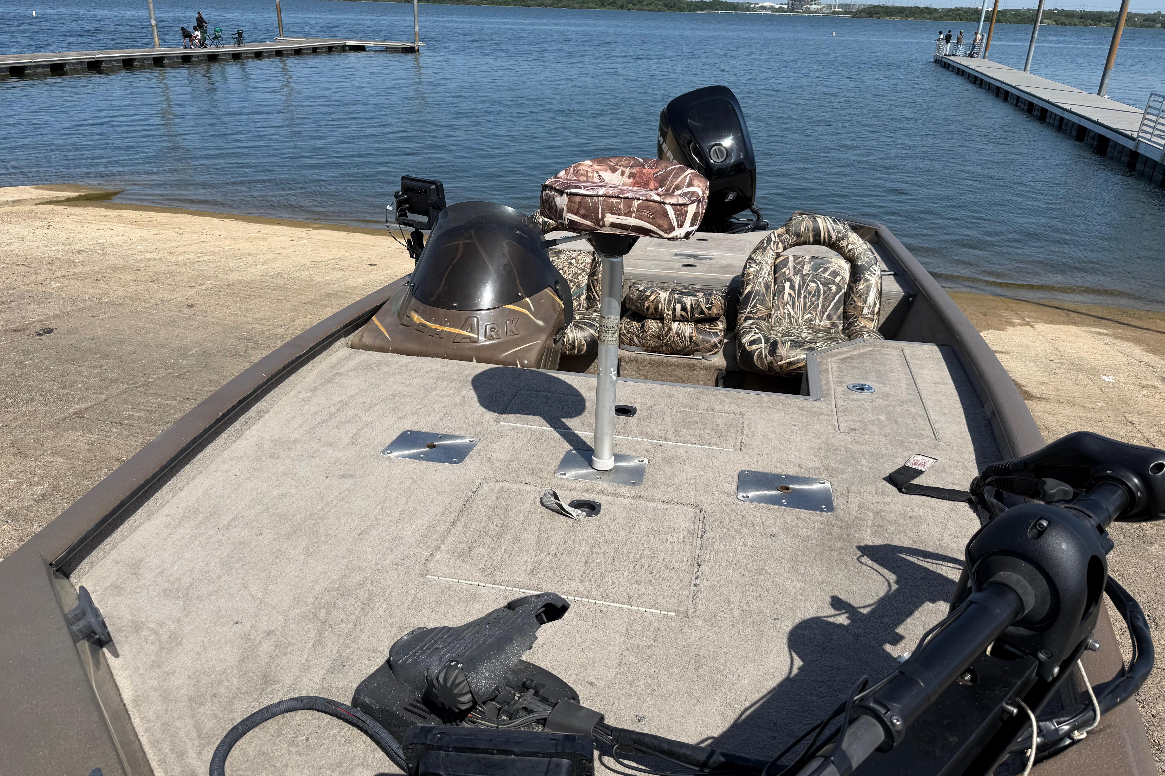 2010 SeaArk Stealth 190 boat at a lakeside dock with camo seats.