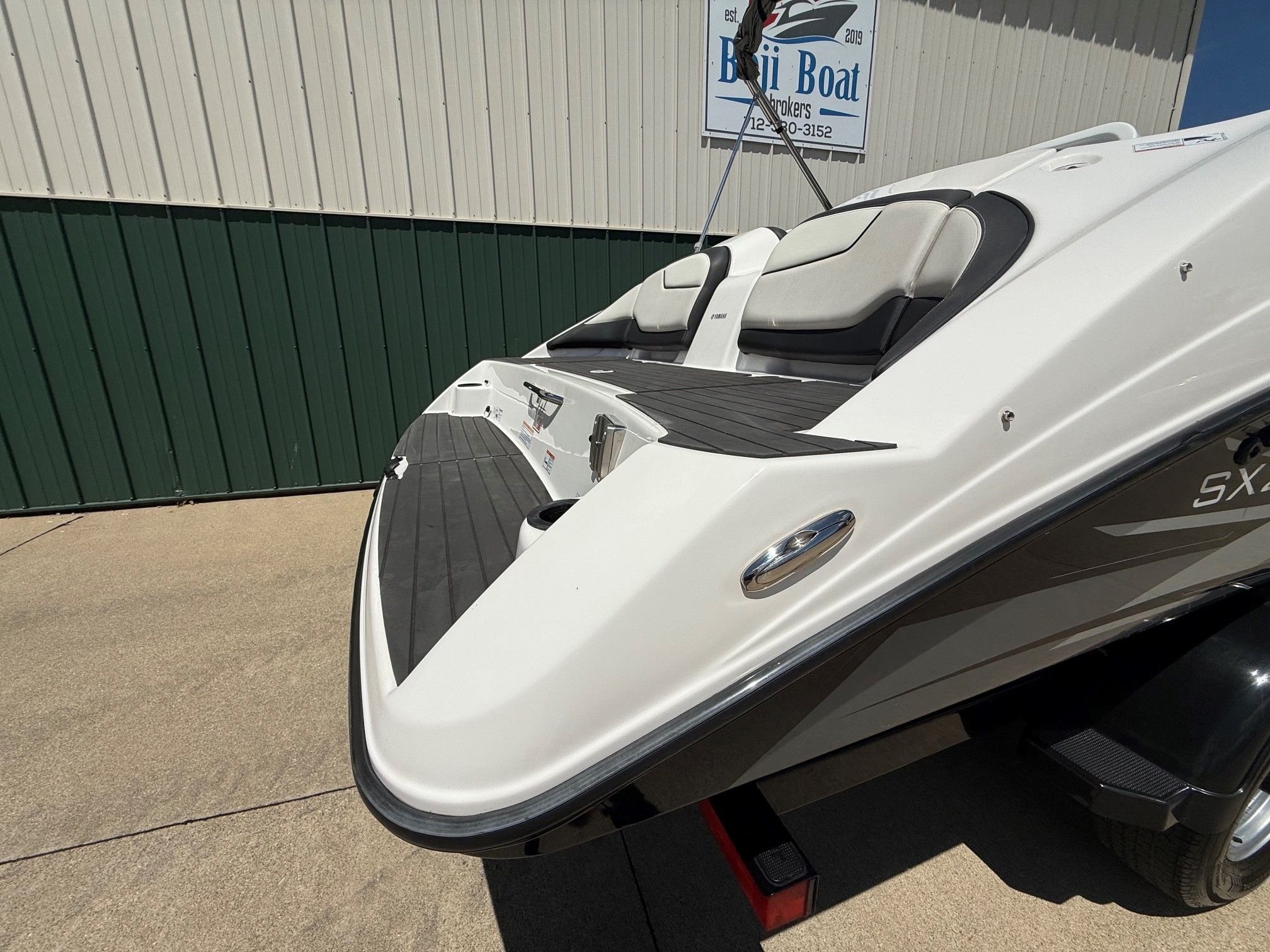 A 2017 Yamaha SX210 boat on a trailer in front of a building.