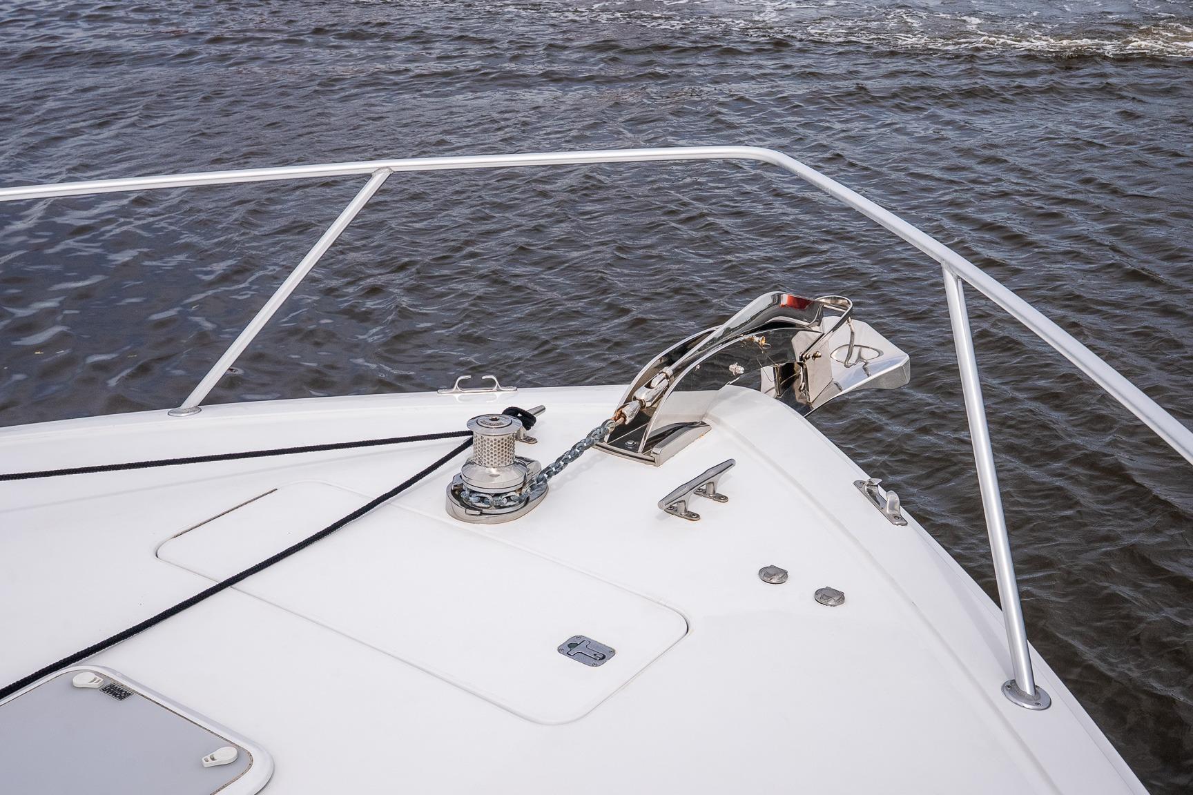 Bow of 2002 Viking 61 Enclosed Bridge yacht with anchor and railing on water.