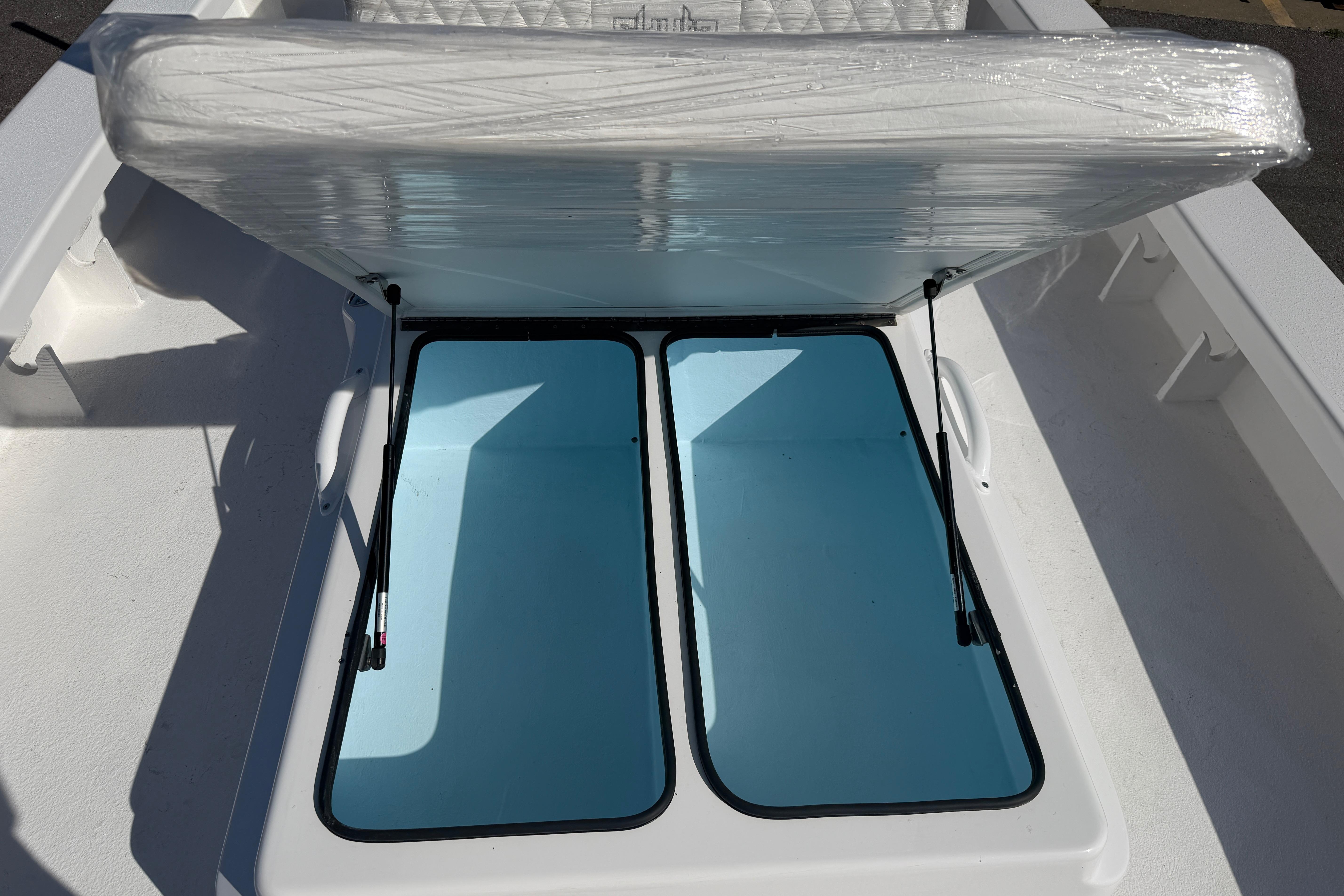 2026 Skuta 24 Cat boat storage compartment with open hatch, revealing spacious interior.