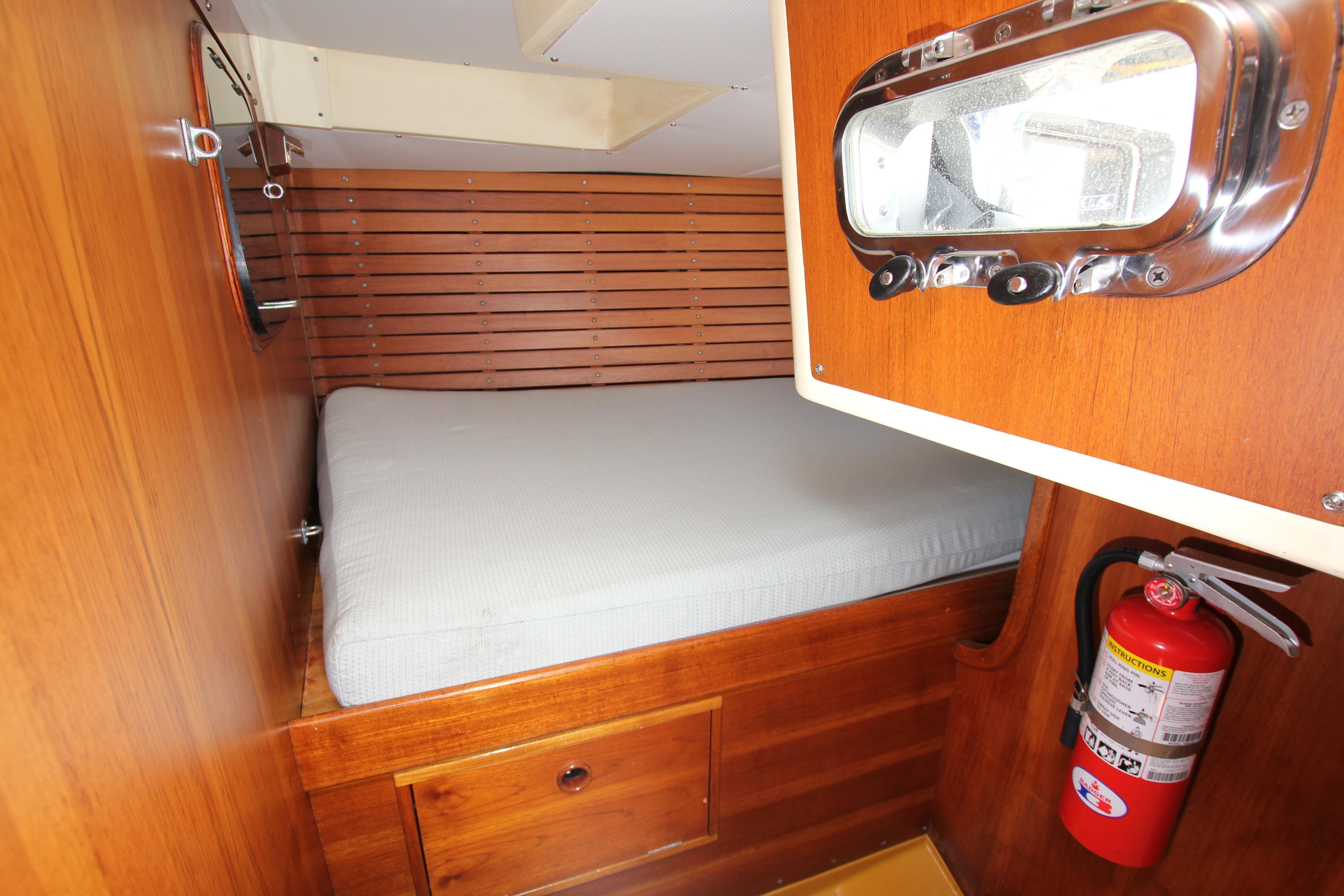 Cozy cabin interior of 1974 Nautor Swan 38 sailboat with wooden finish and fire extinguisher.