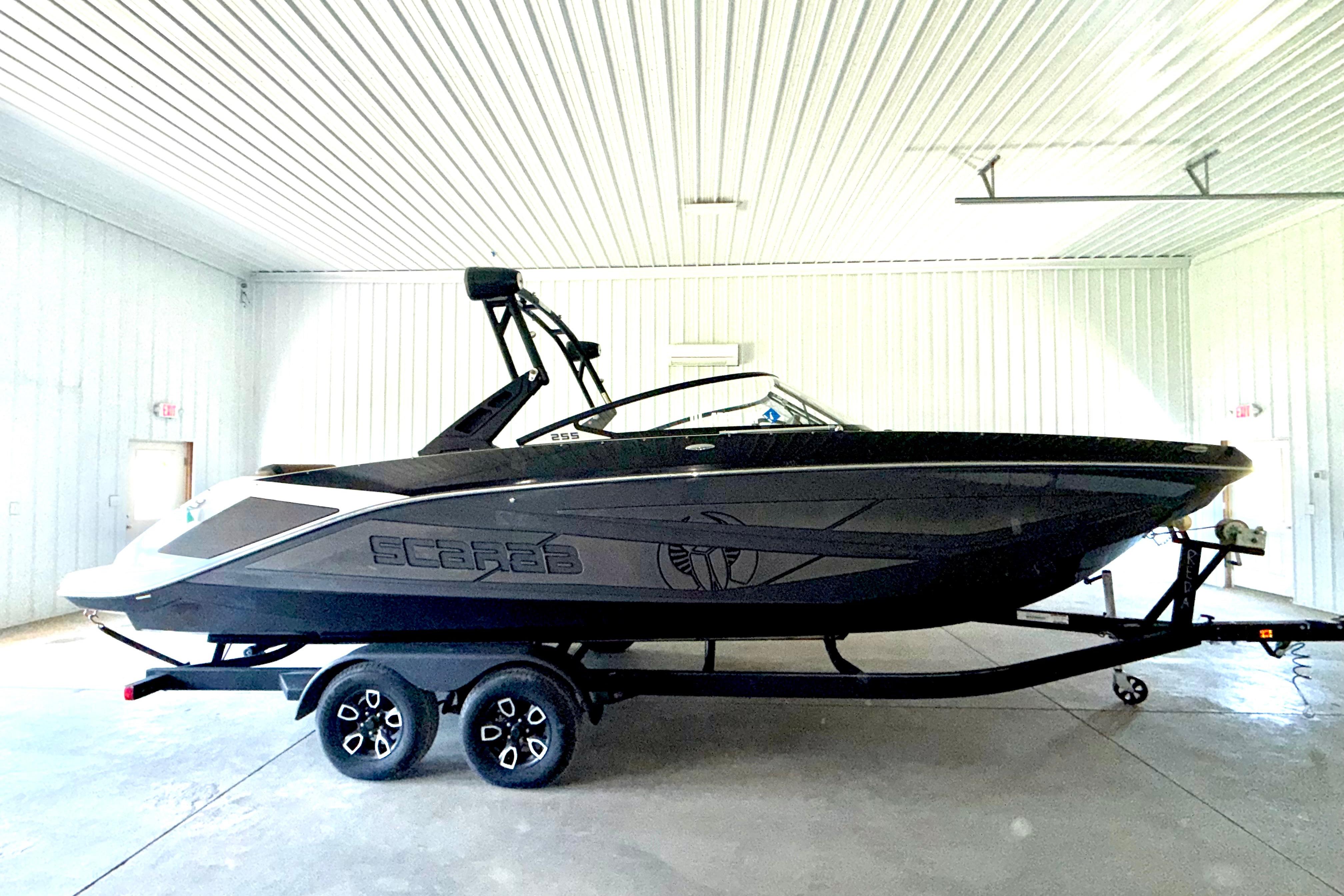 2023 Scarab 255 ID boat in a garage, sleek black design on trailer.