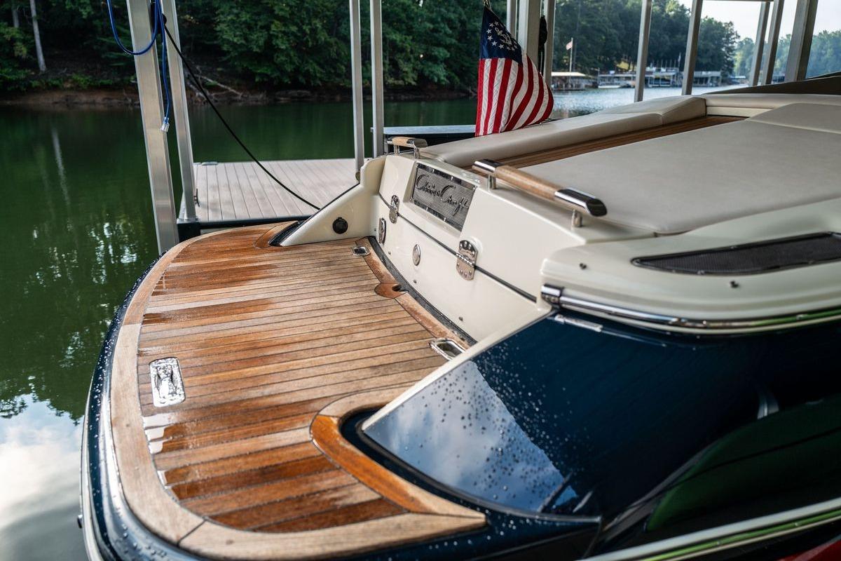 2023 Chris-Craft Launch 27 boat with wooden deck, docked by a serene lake.