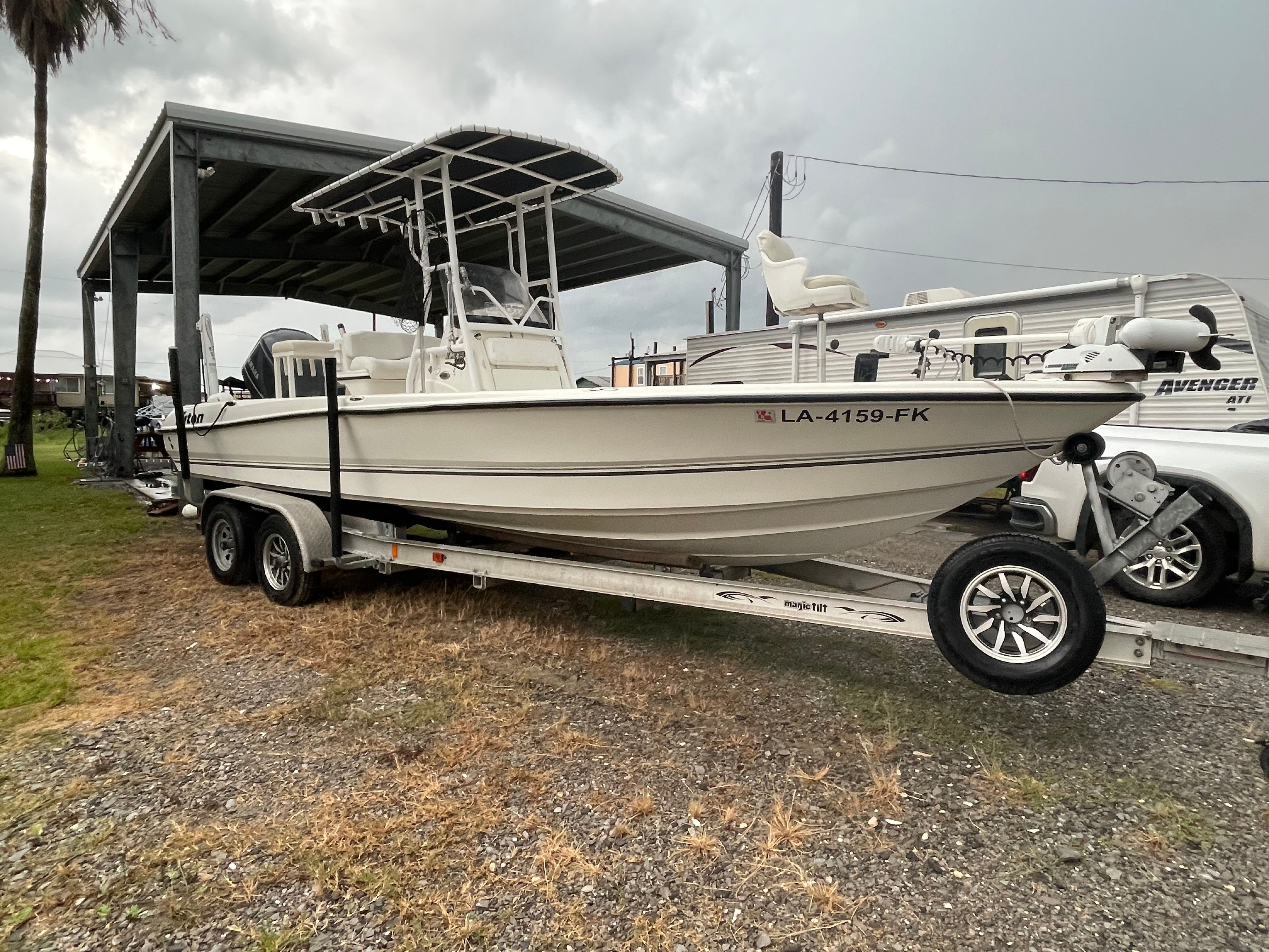 A white 2004 Triton 240 LTS boat on a trailer under a shelter.