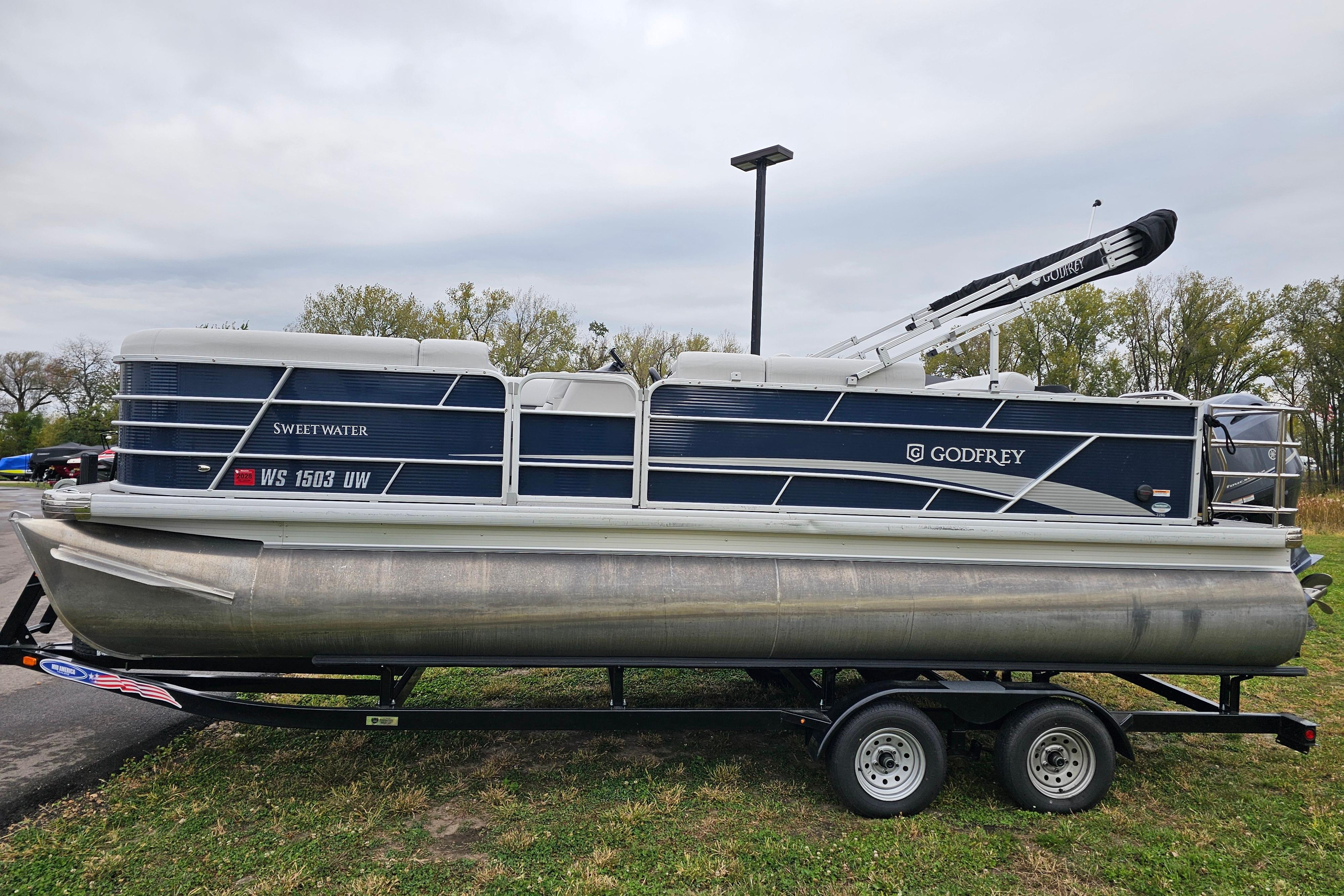 2022 Sweetwater 2286 SFL pontoon boat on trailer, parked outdoors.