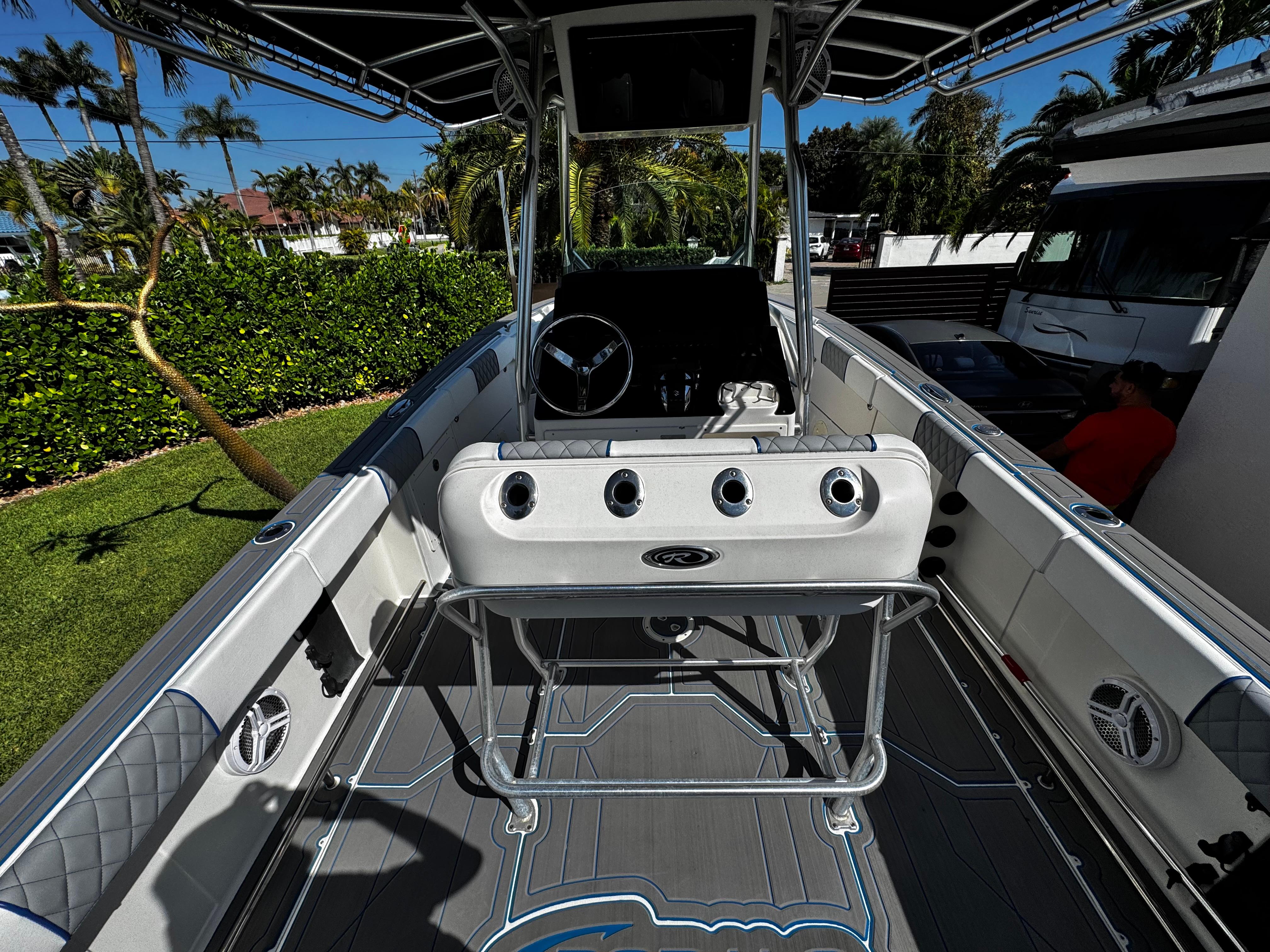 2004 Robalo R 260 boat interior with steering wheel and seating, surrounded by lush greenery.