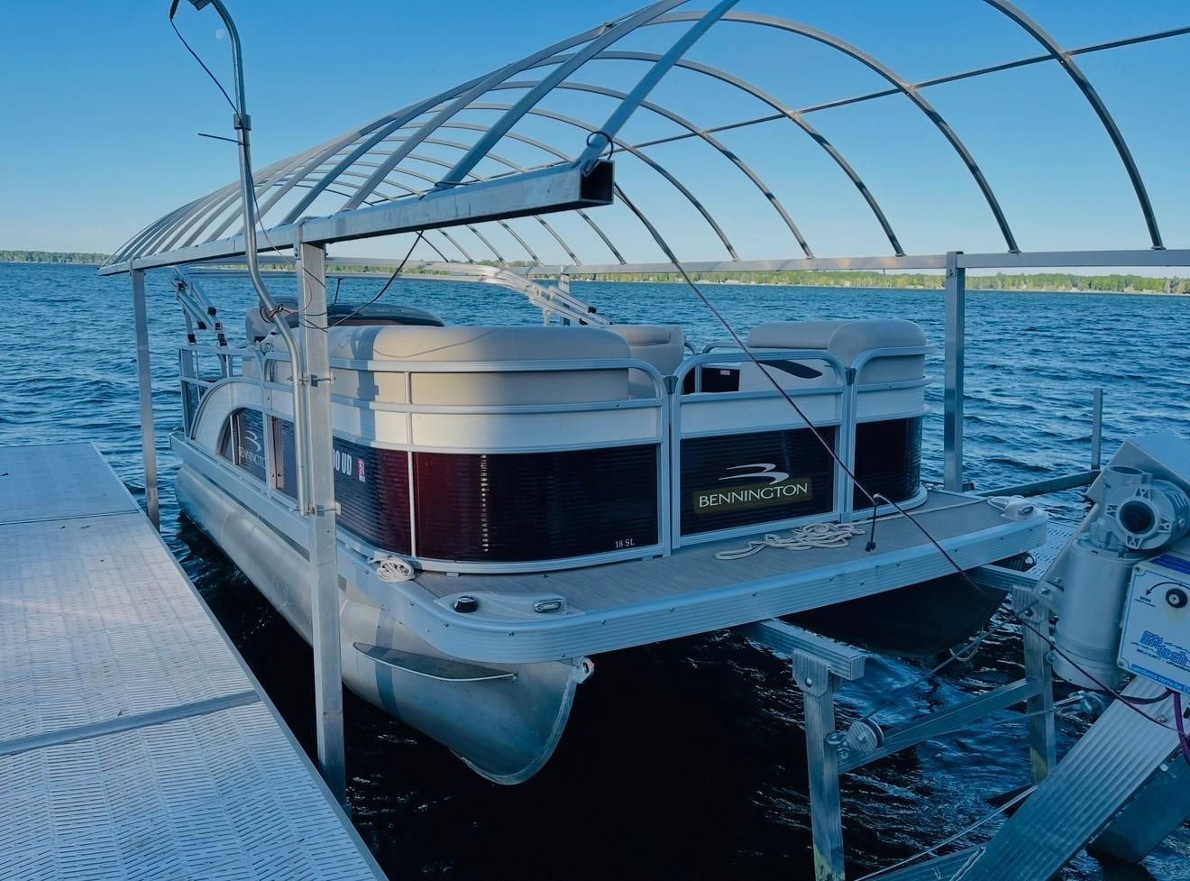 2018 Bennington 18SL pontoon boat on a boat lift by the lake.