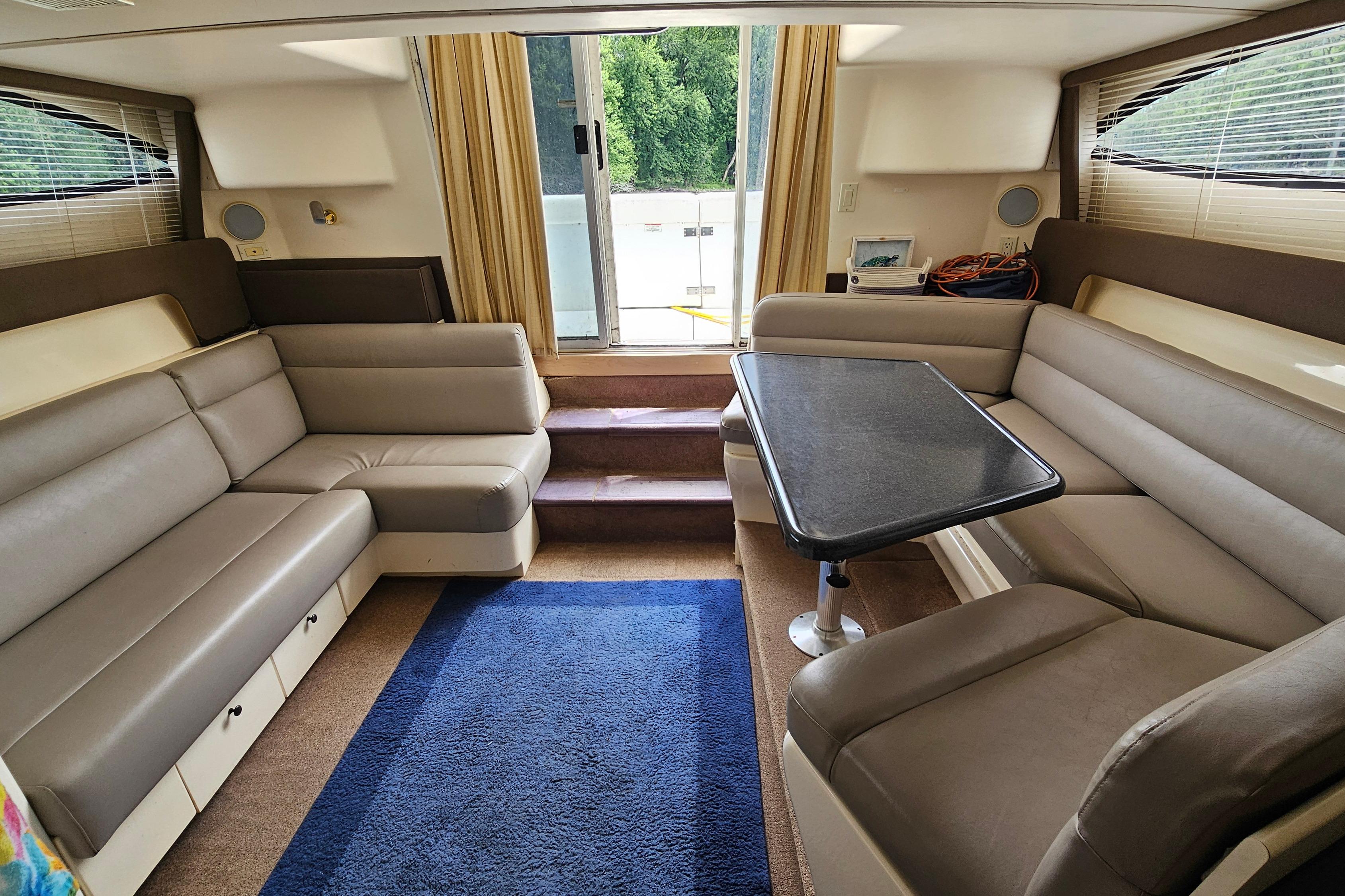 Interior of a 1999 Carver 350 Mariner yacht with beige seating and a central table.