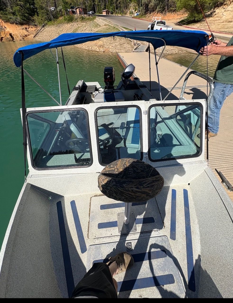A 2002 Stryker Rogue boat with a blue canopy, docked at a pier.