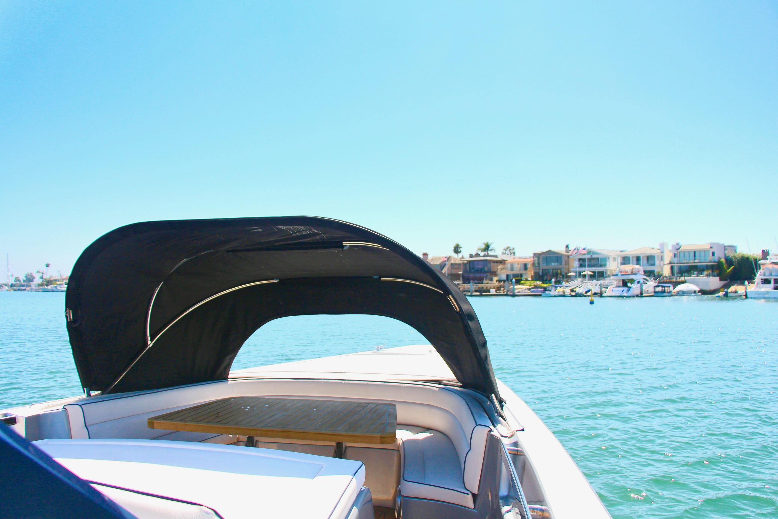 Maori 50 boat (2017) with canopy on calm water near coastal homes.