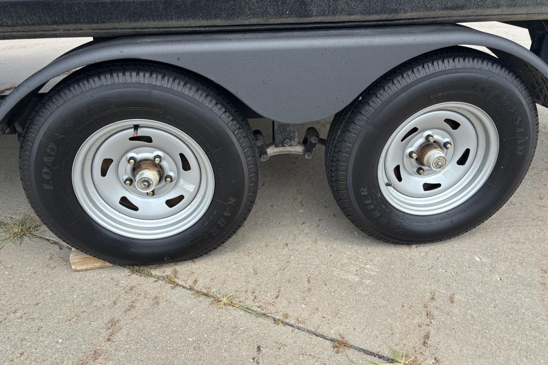 Trailer wheels of a 2023 Sun Tracker SportFish 20 DLX on concrete surface.