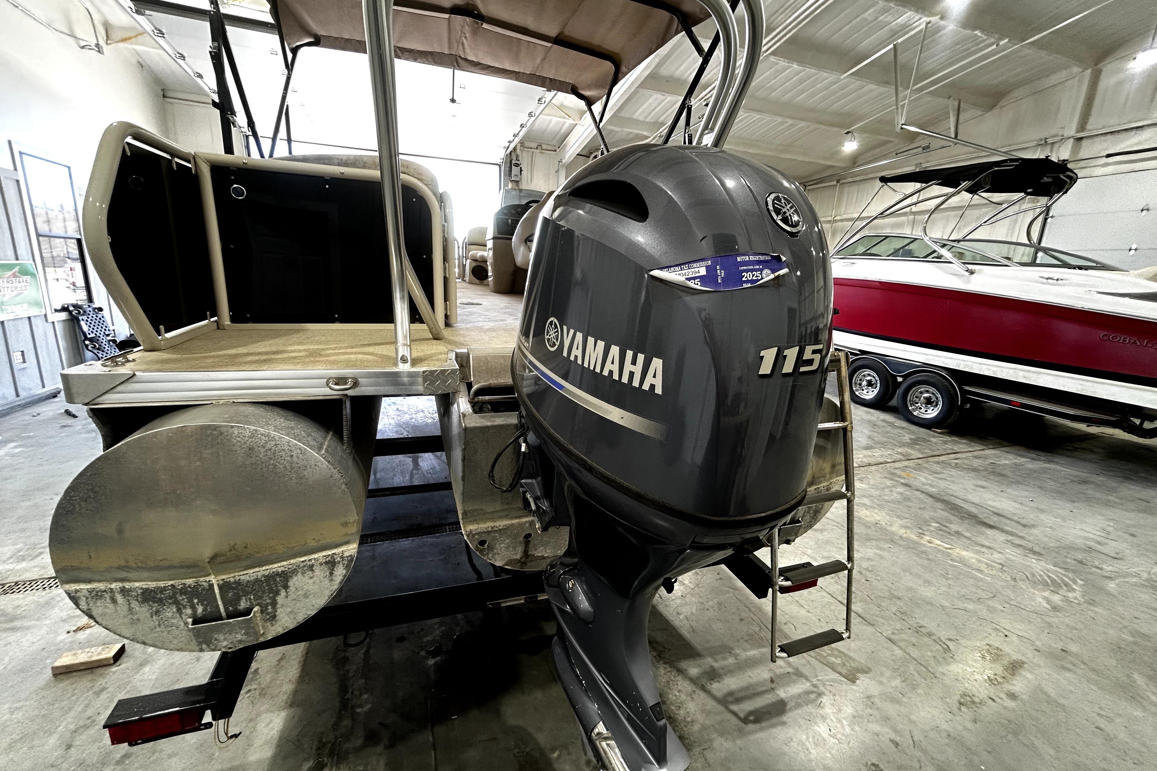 2021 Aloha Pontoon Tropical Series with Yamaha 115 engine in a boat storage facility.