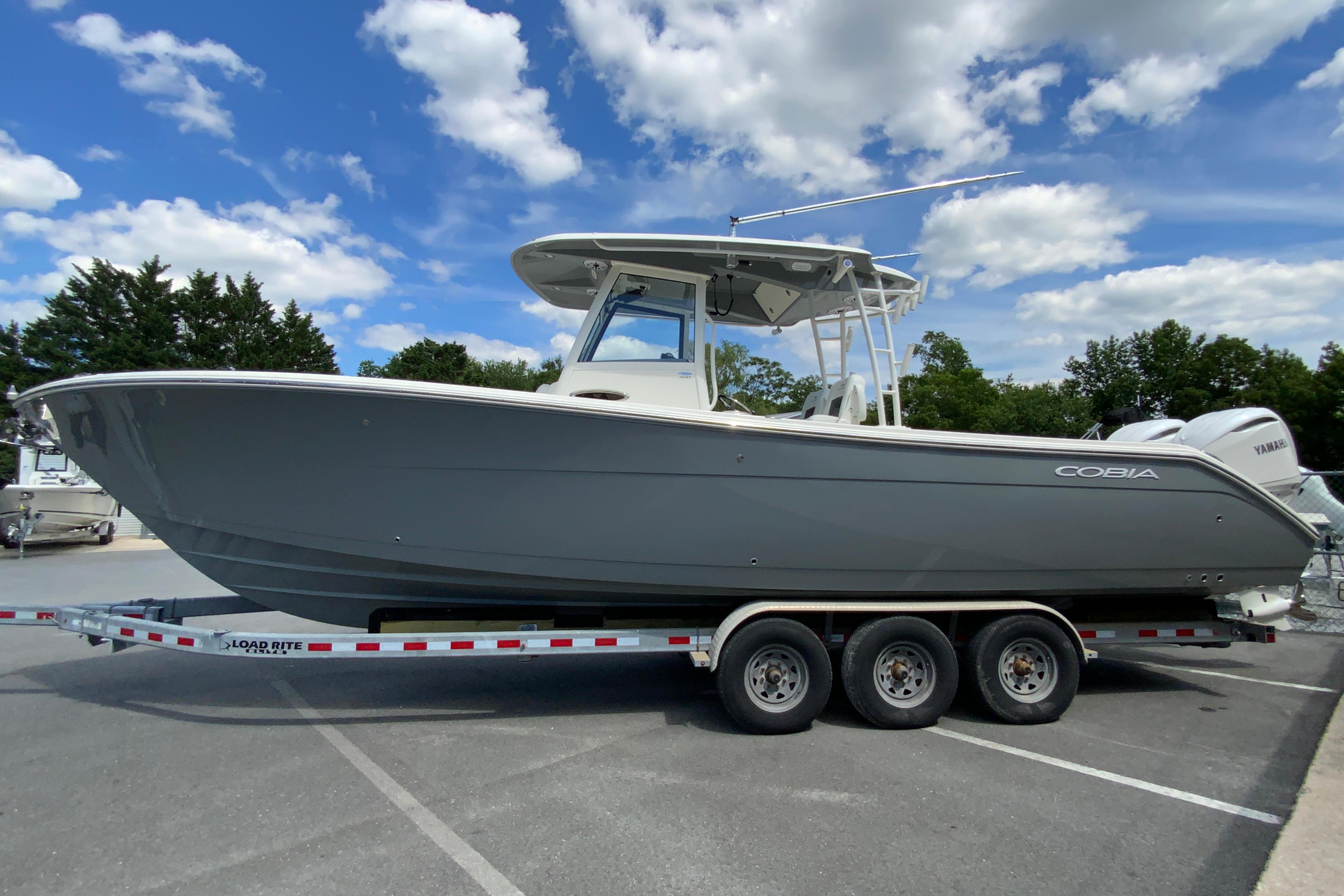 2027 Cobia 320 Center Console boat on trailer under blue sky.
