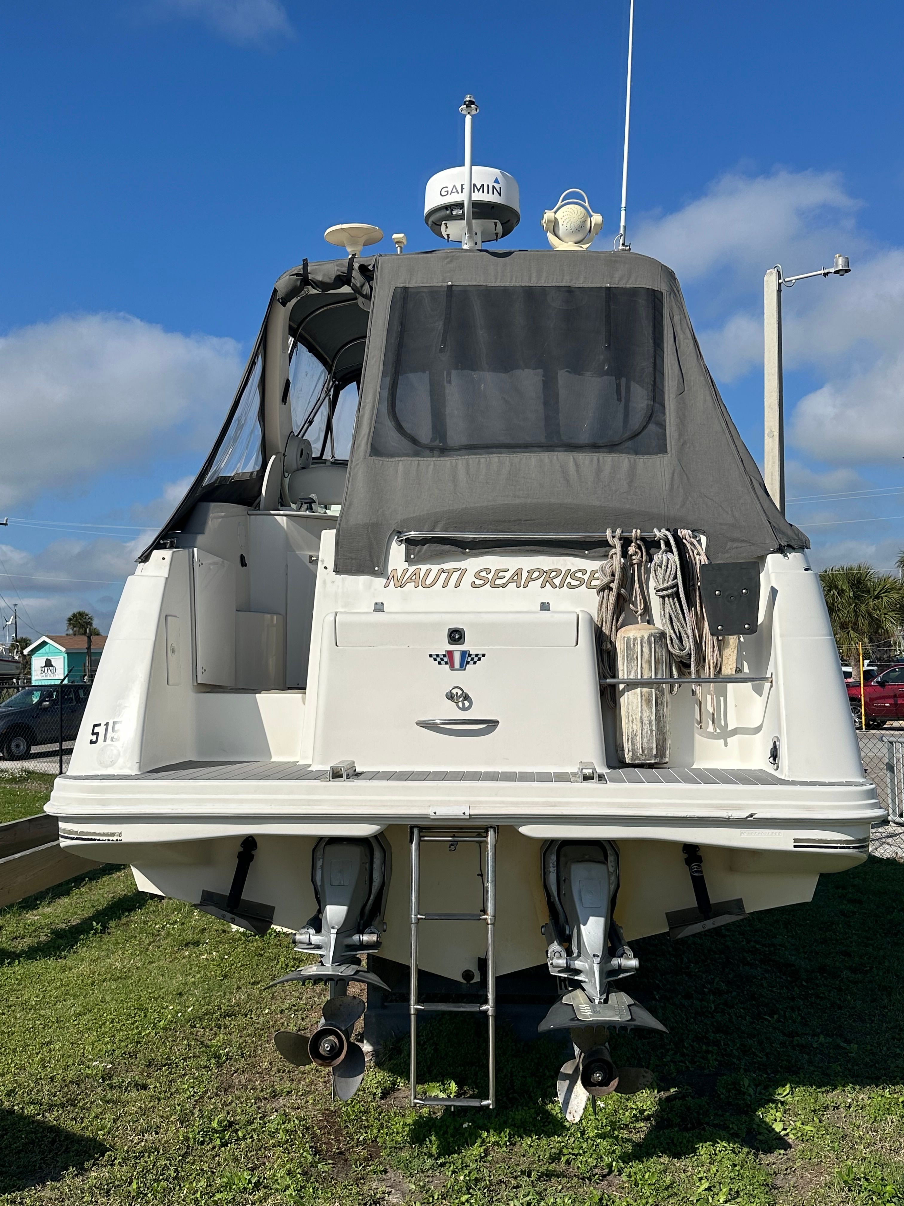 Rear view of a 1999 Wellcraft 3000 Matrinique boat on grass.