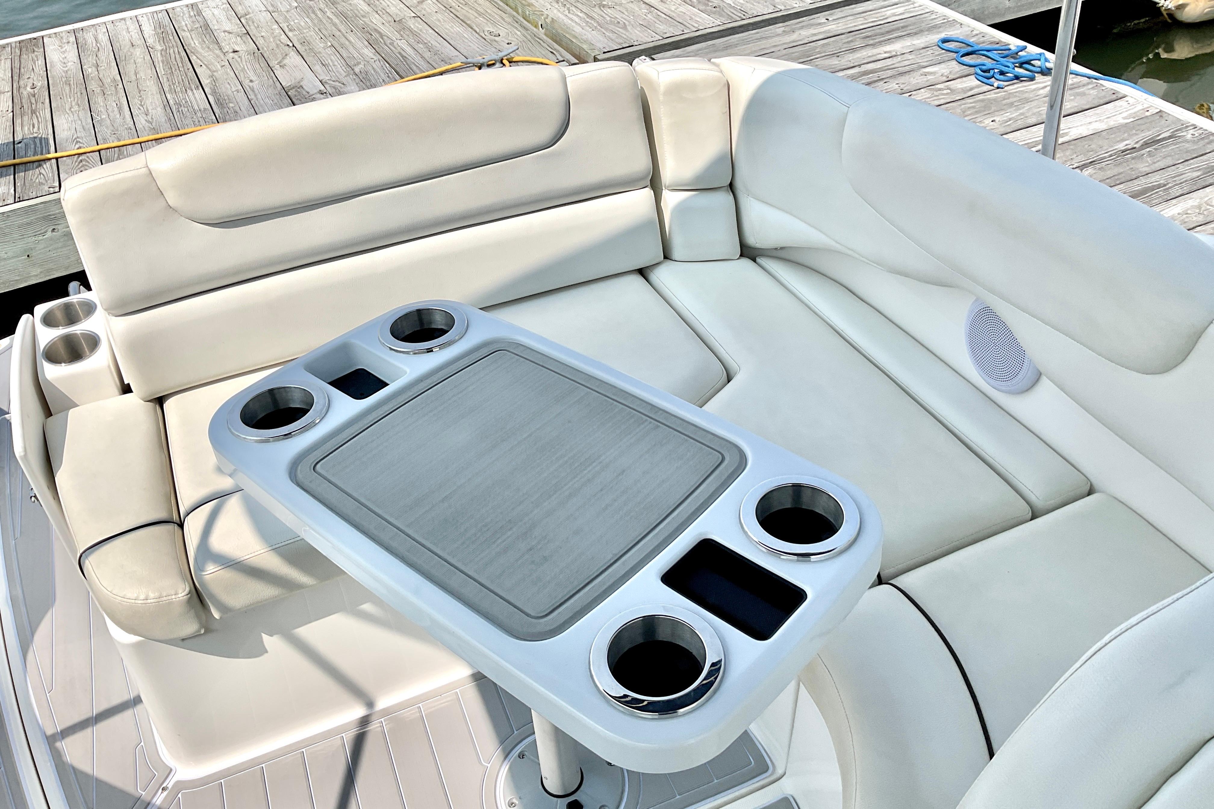 2013 Rinker 290 Express Cruiser interior with cushioned seating and table, docked at marina.