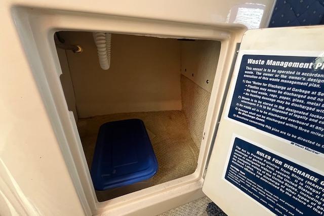 2003 Sea Ray 260 Sundancer storage compartment with waste management instructions.