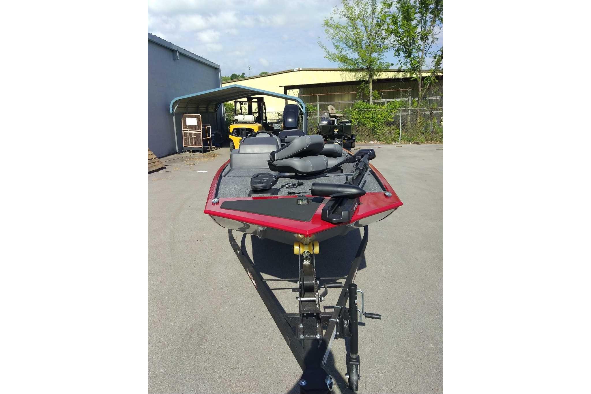 2026 Tracker Bass Tracker Classic XL boat in a parking area, featuring a sleek red design.