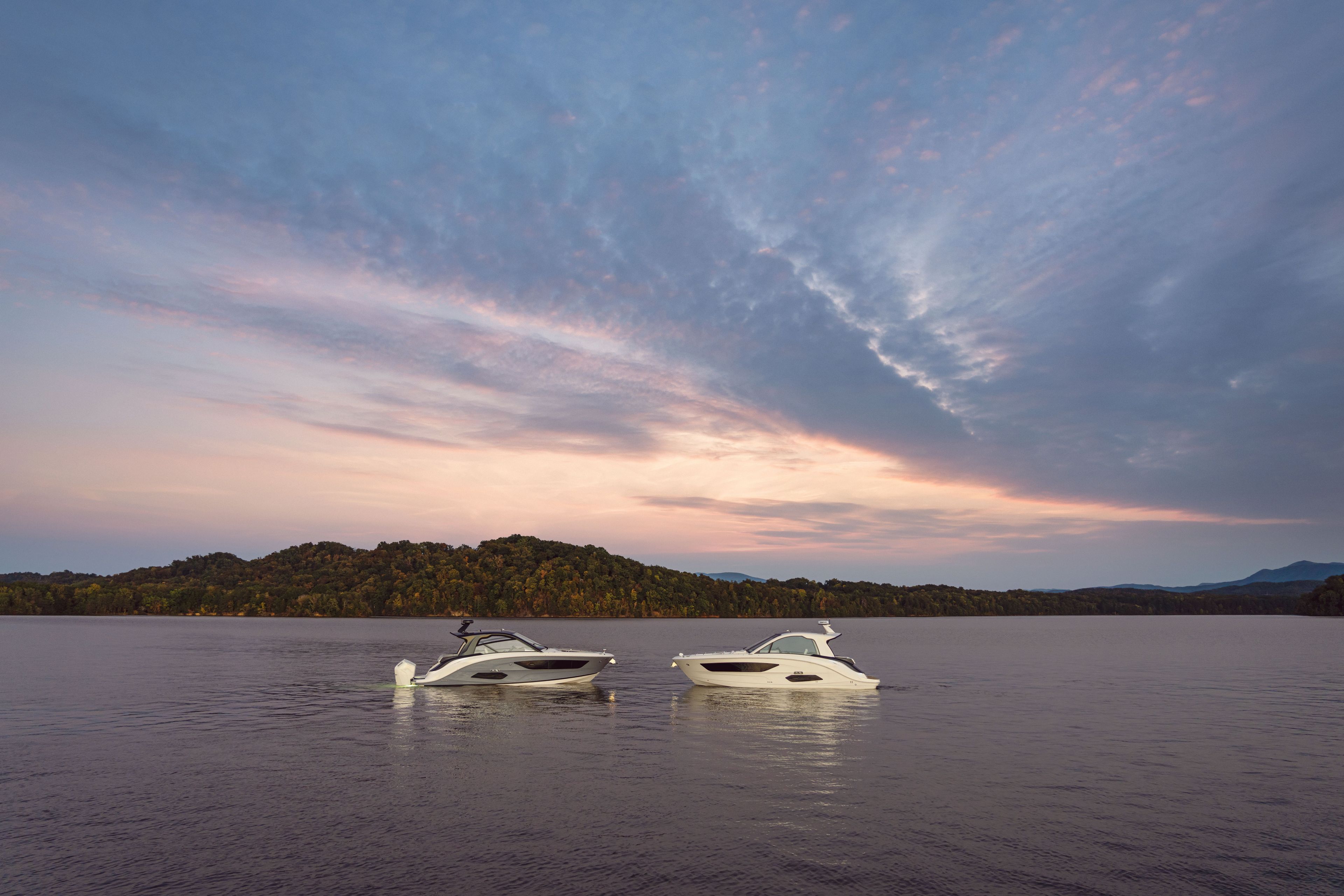 Two Sea Ray Sundancer 370 Outboard boats float on calm water at sunset.