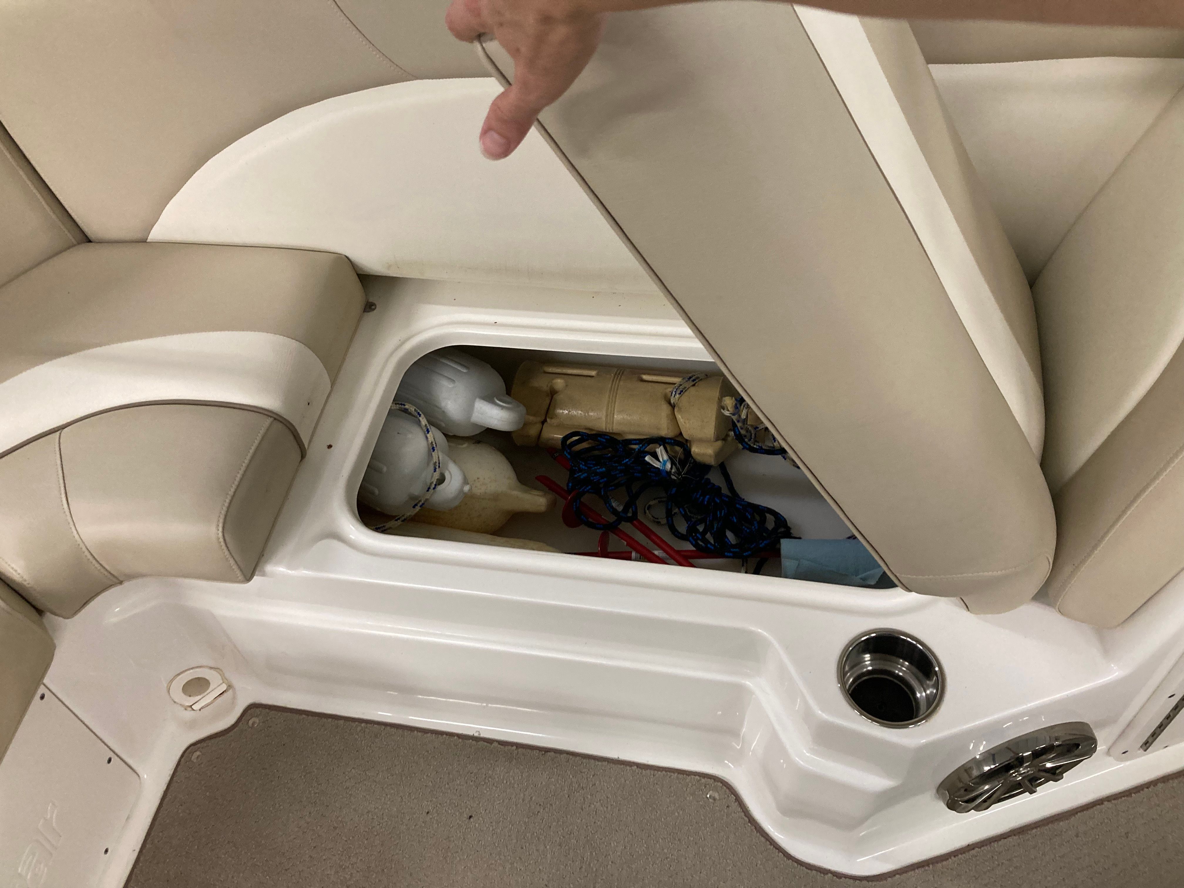A seat cushion is lifted to reveal a storage compartment with ropes and equipment.