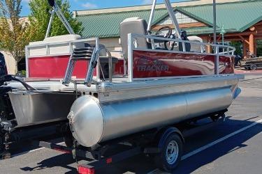 2026 Sun Tracker Bass Buggy 16 XL Select pontoon boat on trailer in parking lot.