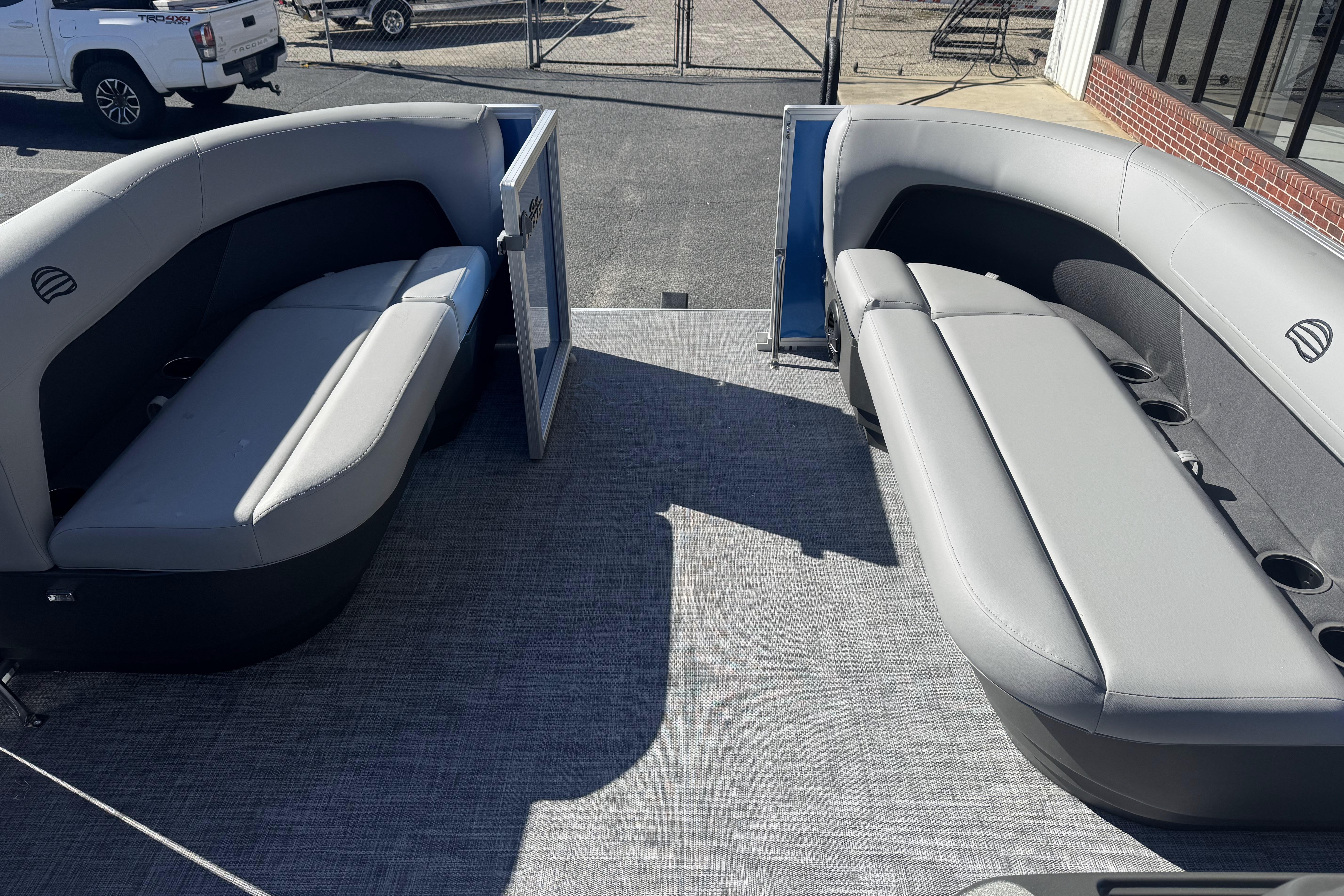 2026 Sun Tracker Party Barge 16 DLX interior with gray seating and open gate.