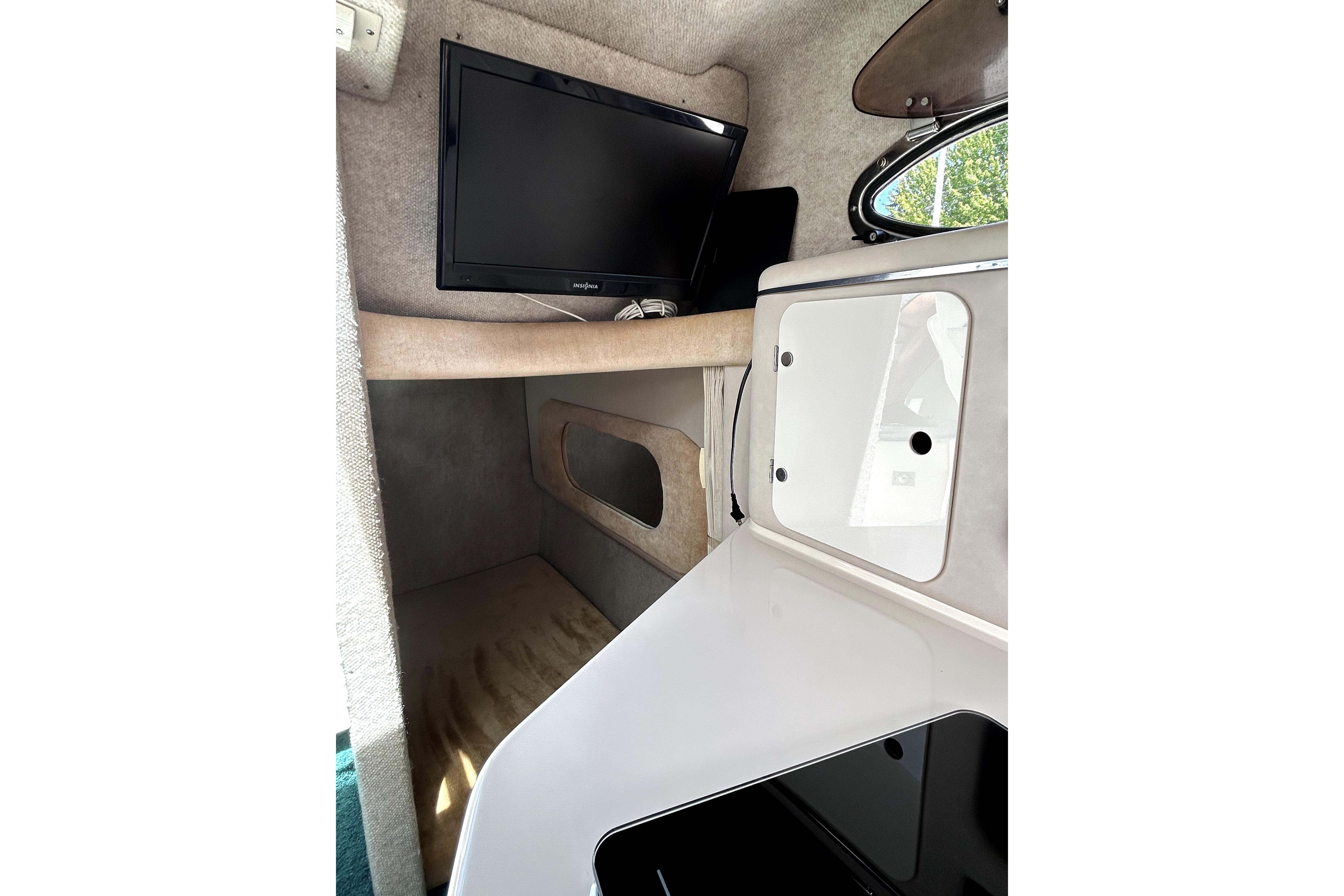 Interior cabin of 1995 Sea Ray 250 Sundancer with TV and storage compartment.