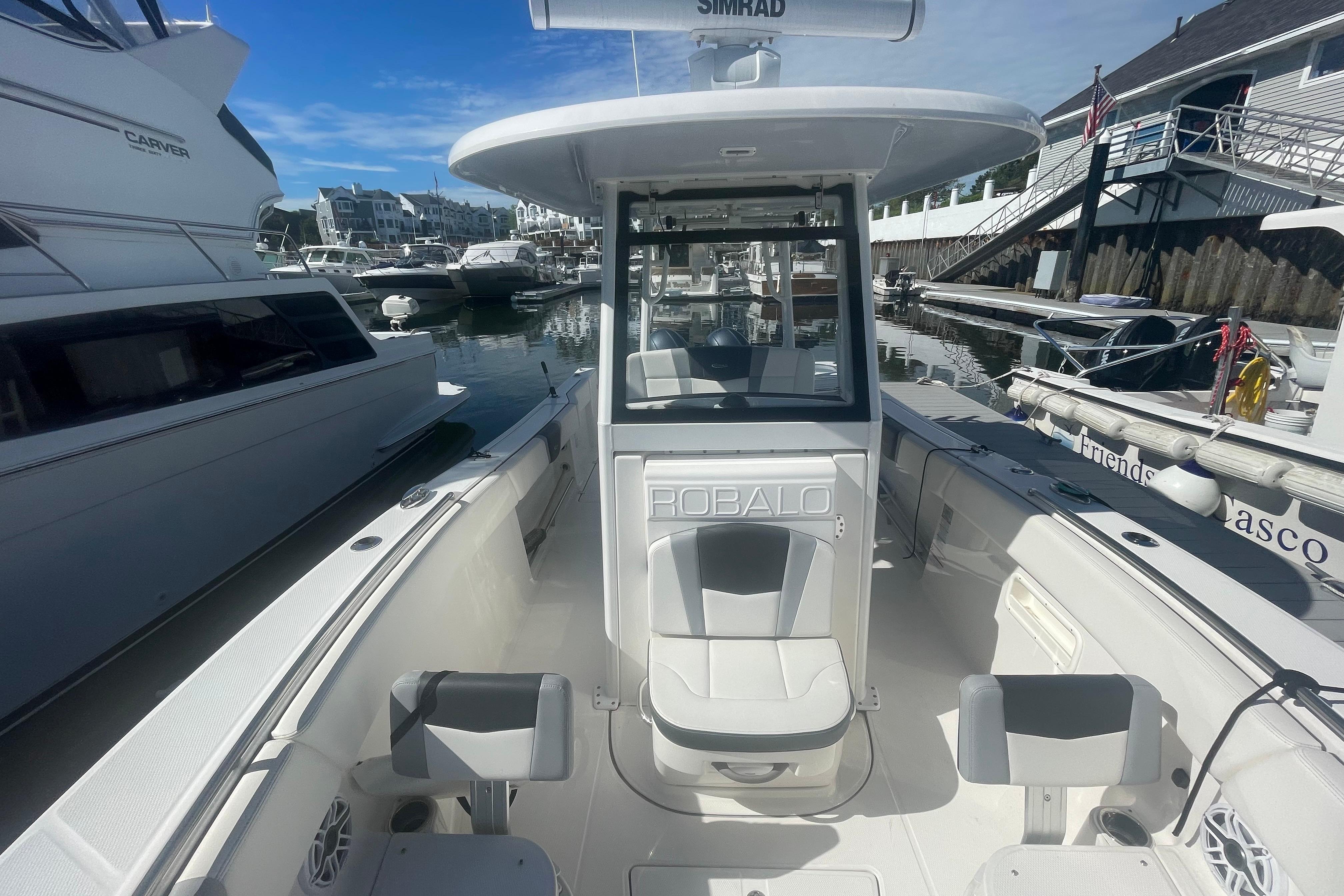 2023 Robalo R270 Center Console boat docked in a marina under clear blue skies.