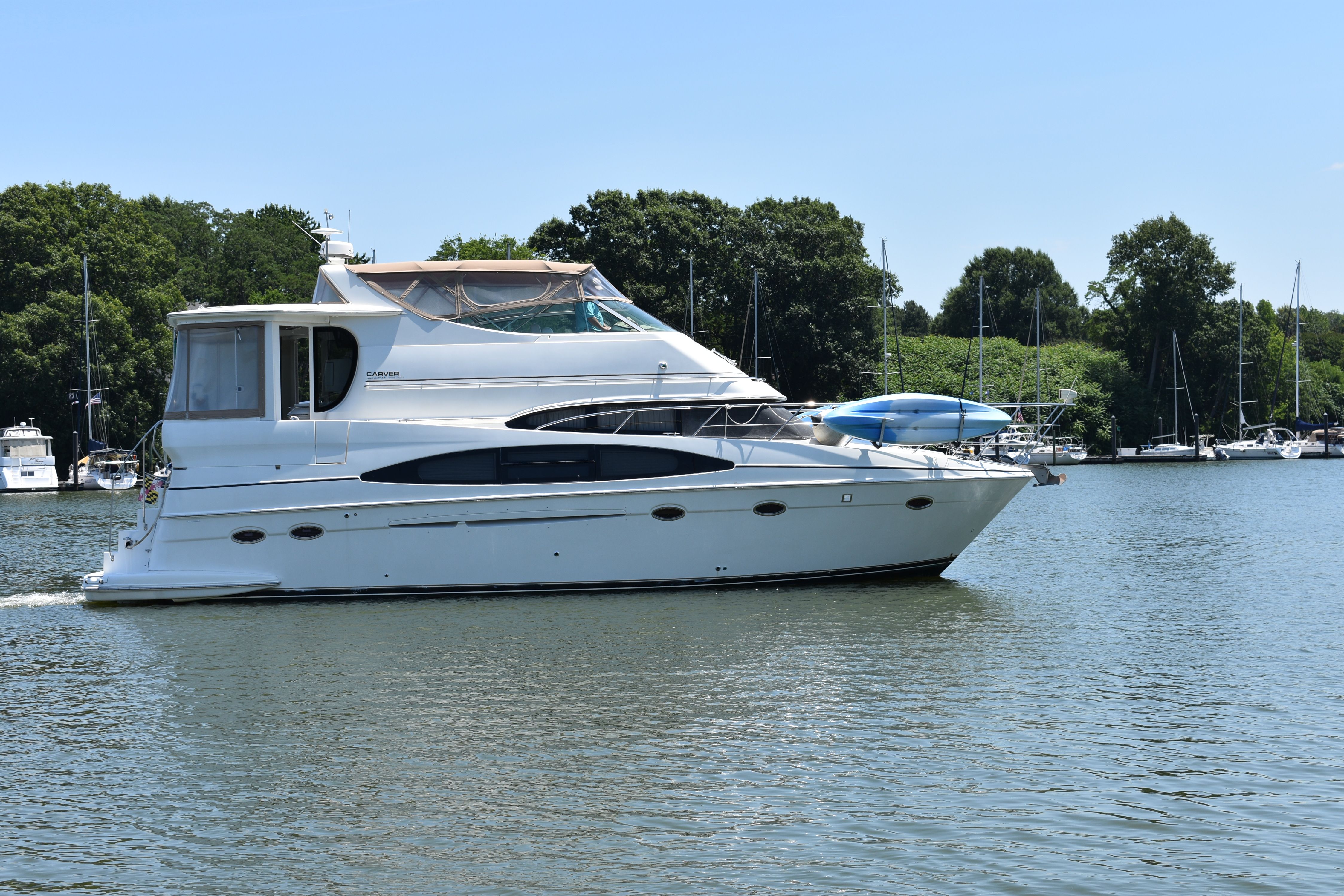 A 2004 Carver 466 Motor Yacht cruising on calm water, surrounded by trees.