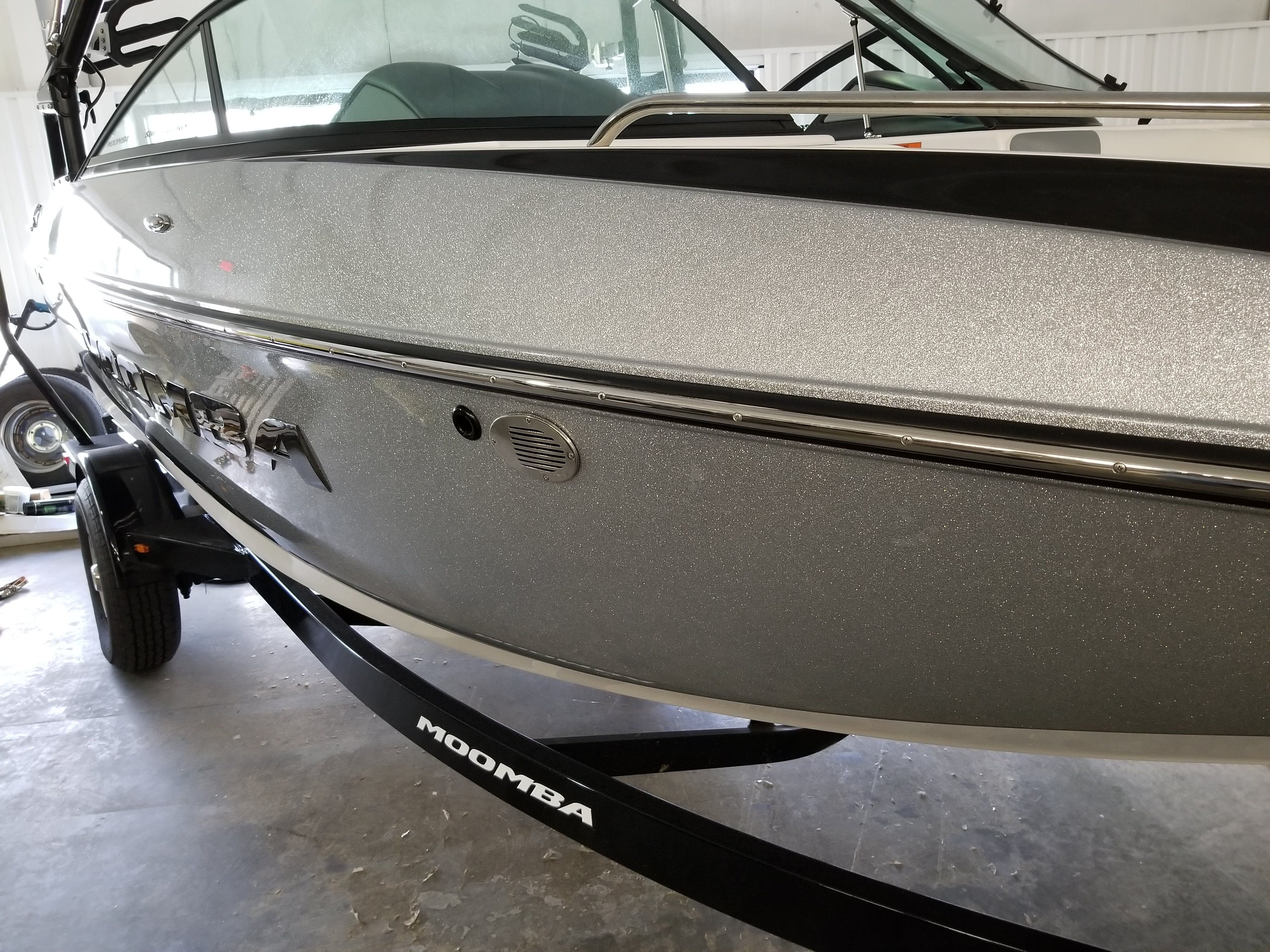 A silver 2016 Moomba Mondo boat on a trailer inside a warehouse.