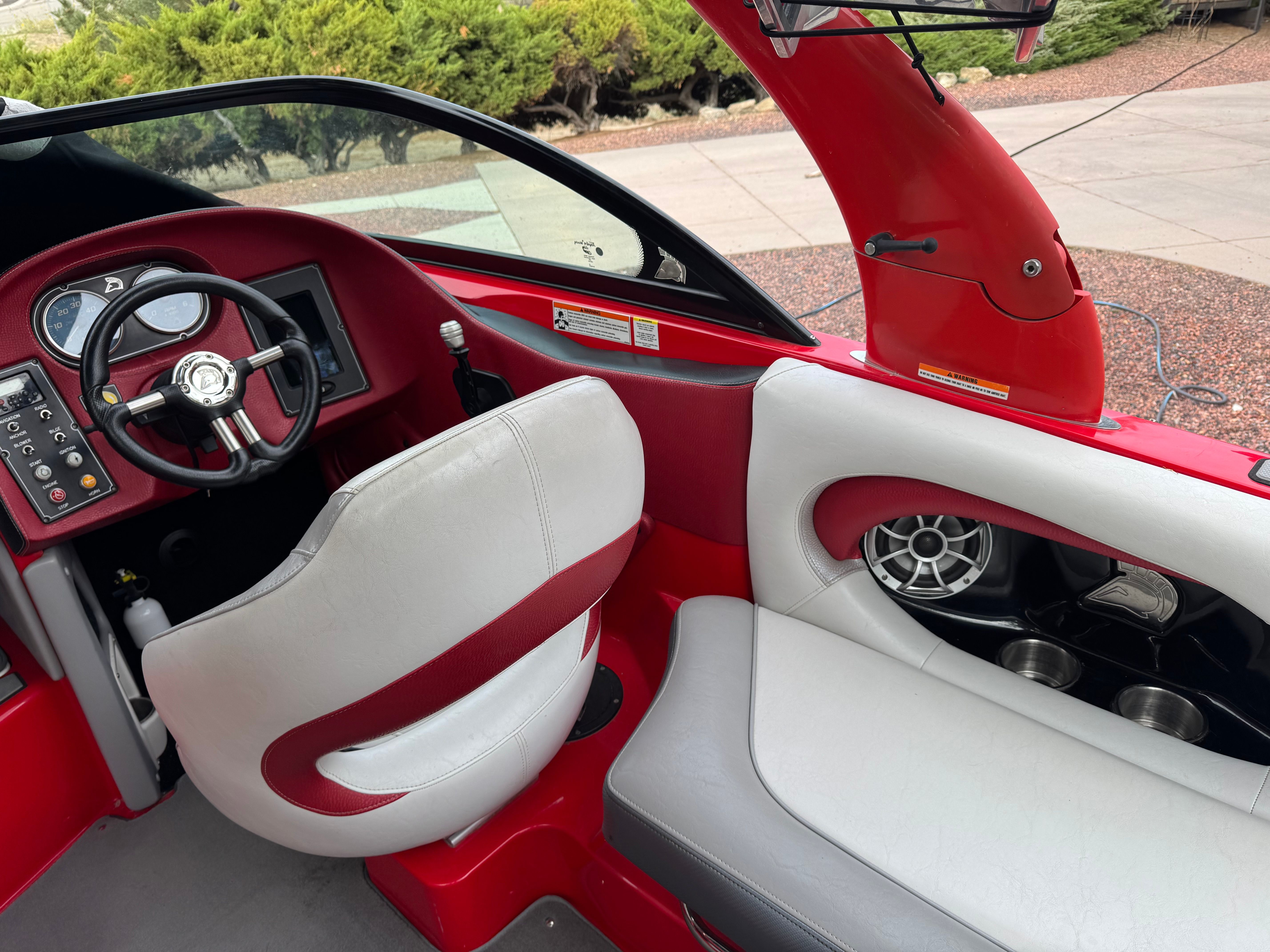 The image shows the cockpit of a 2013 Centurion Enzo SV211. It features red and white seats, a steering wheel, and a dashboard with instruments.