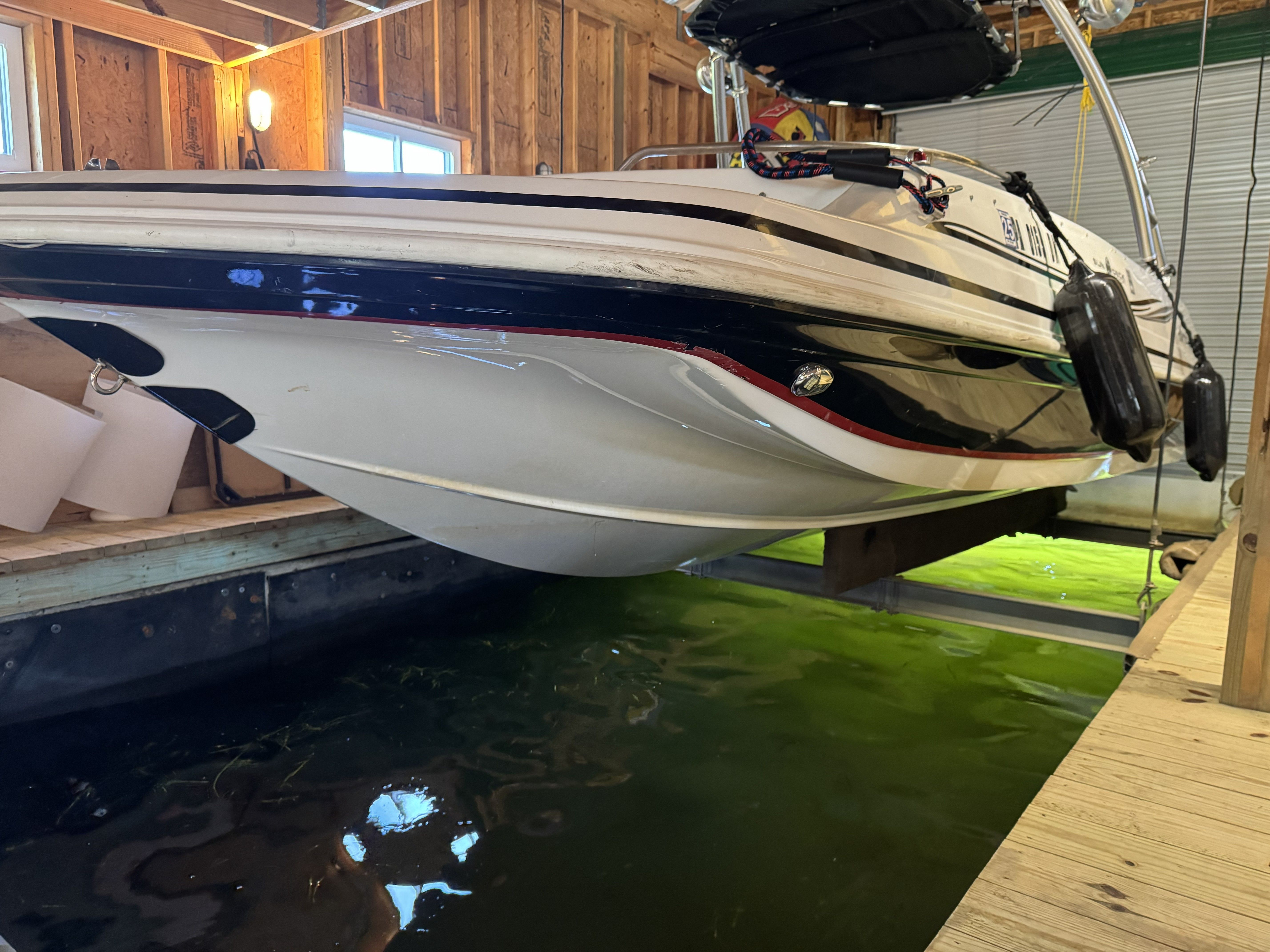 A 2014 Hurricane SS201 I/O boat in a boathouse above the water.