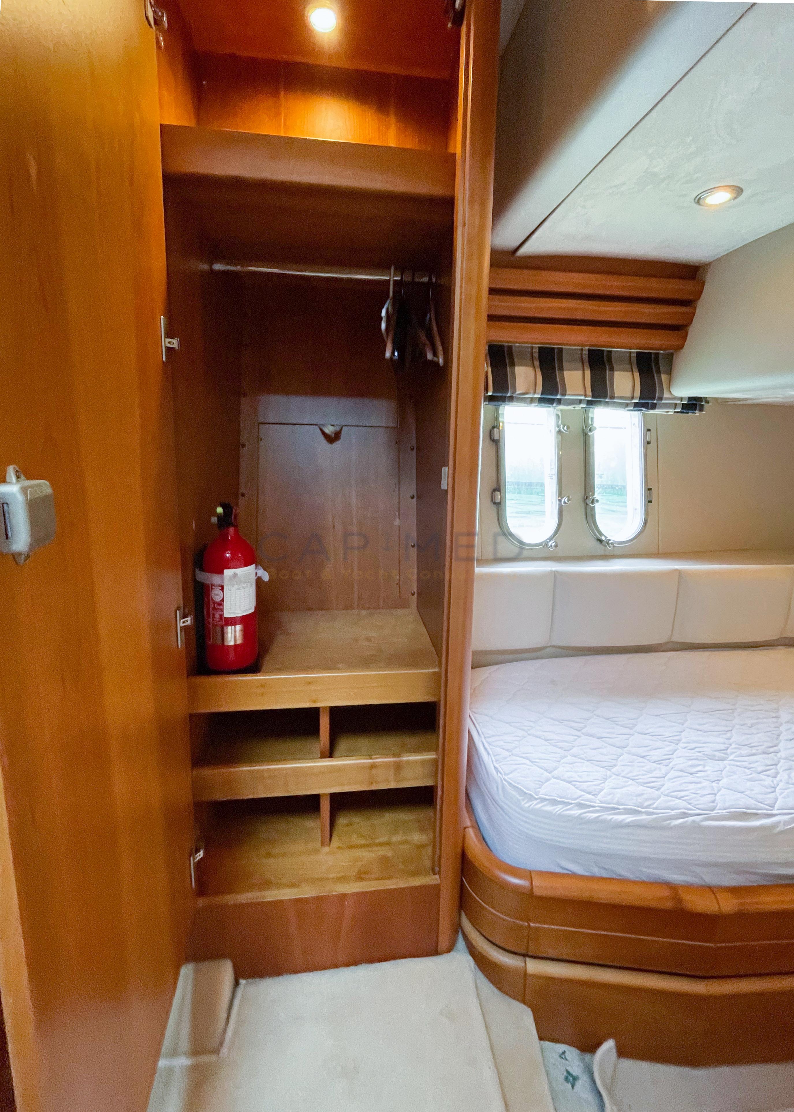 Wooden yacht cabin interior with closet, fire extinguisher, and bed. Pearl 60, 2006 model.