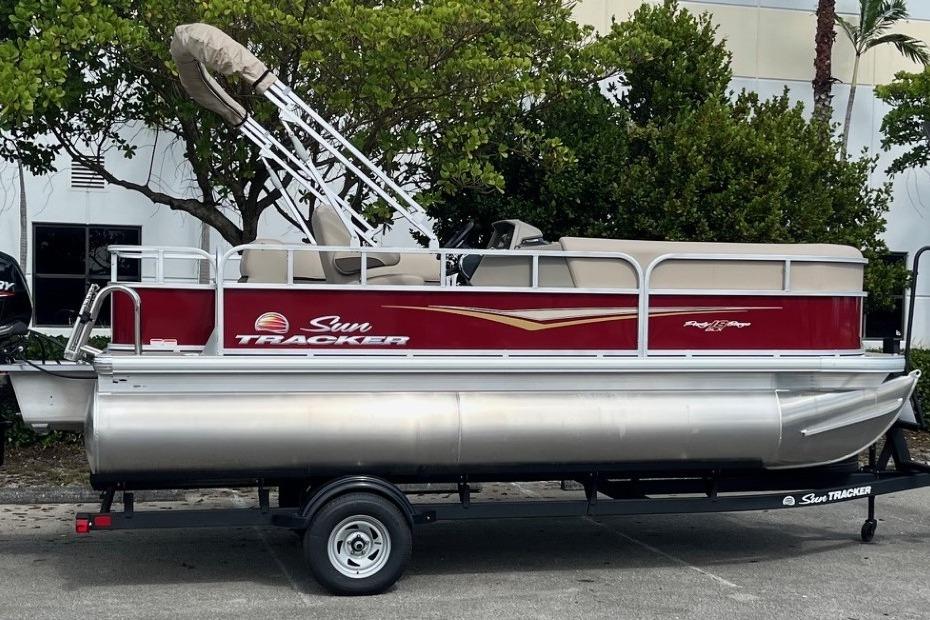2025 Sun Tracker Party Barge 18 DLX pontoon boat on trailer, parked outdoors.