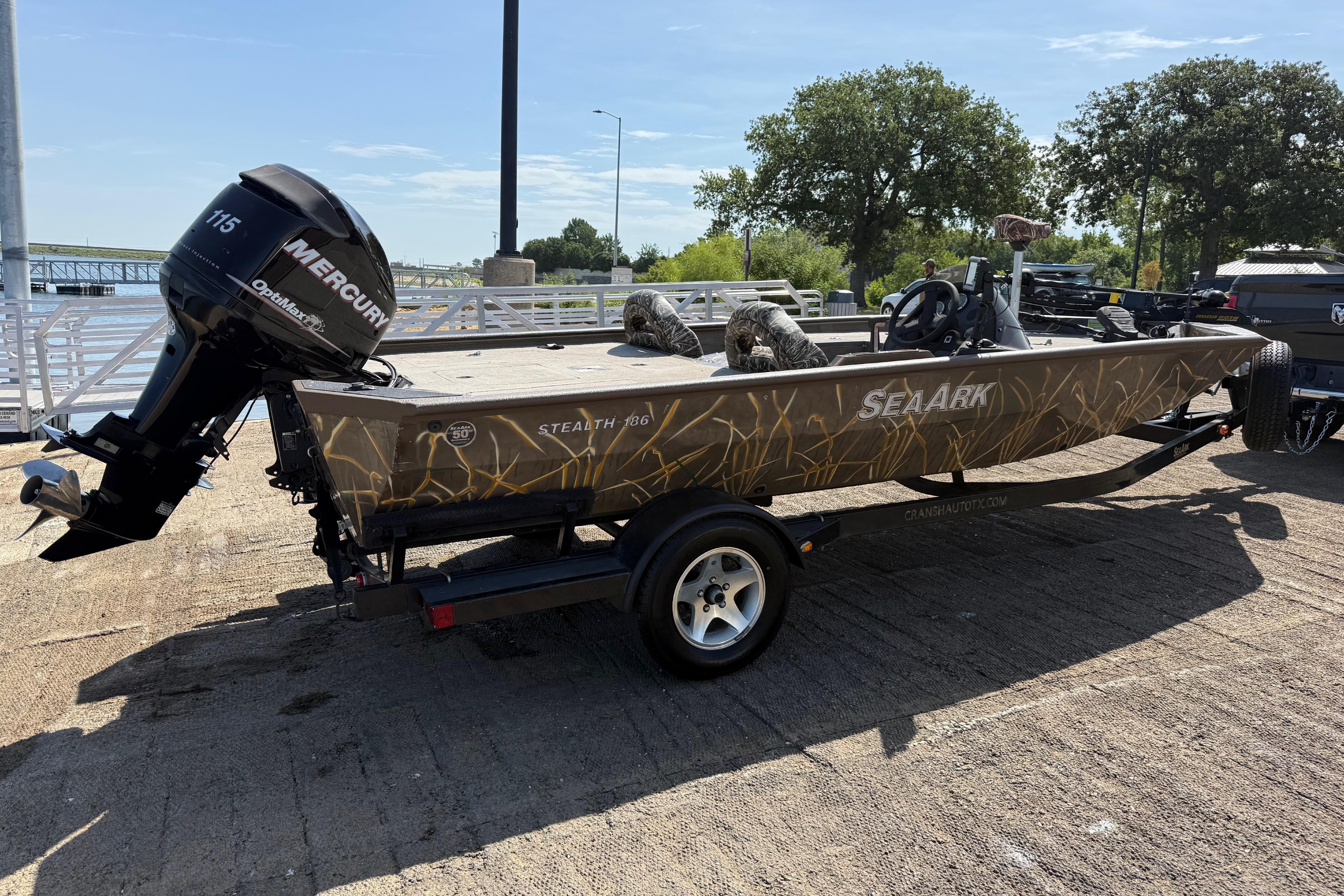 2010 SeaArk Stealth 190 boat with Mercury engine on trailer, parked near a dock.