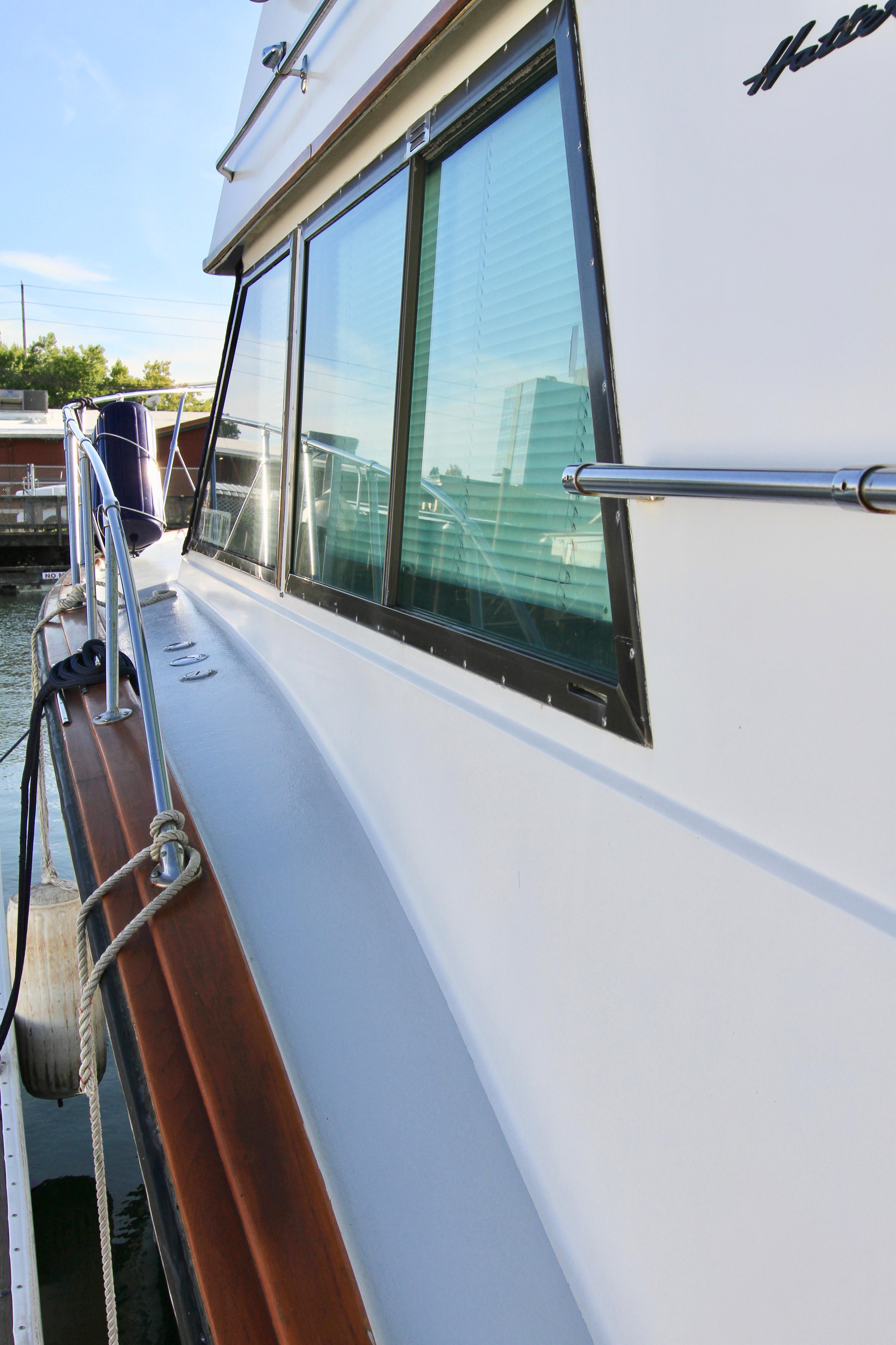 Side view of a 1977 Hatteras 37 Convertible yacht docked at a marina.