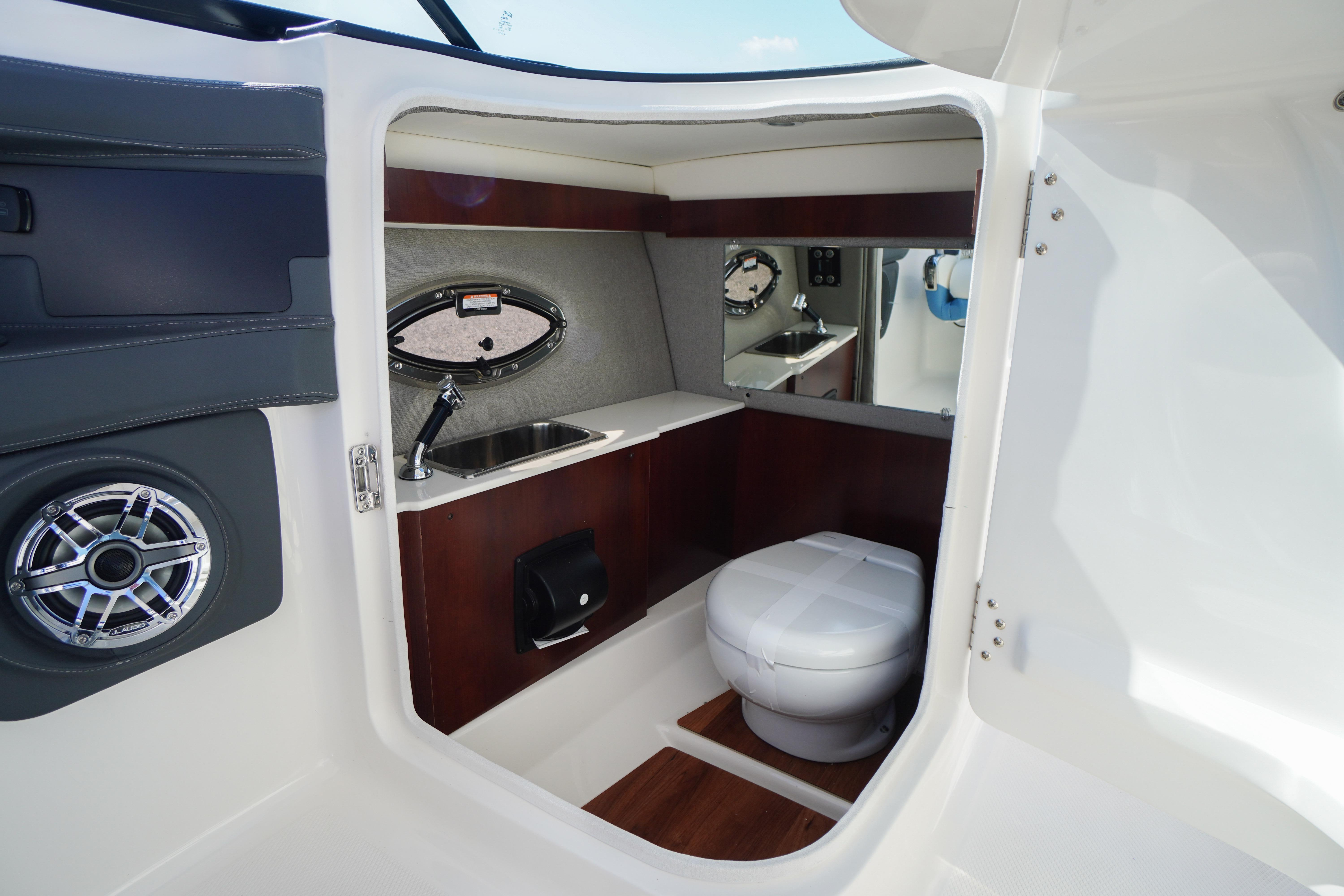 Interior of 2026 Chaparral 270 OSX boat featuring a compact bathroom with sink and toilet.