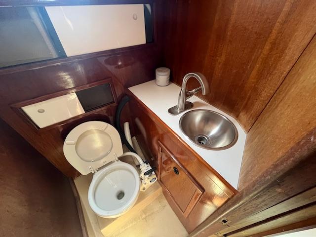 1974 C&C 35 MkII yacht bathroom with wooden cabinetry, sink, and toilet.