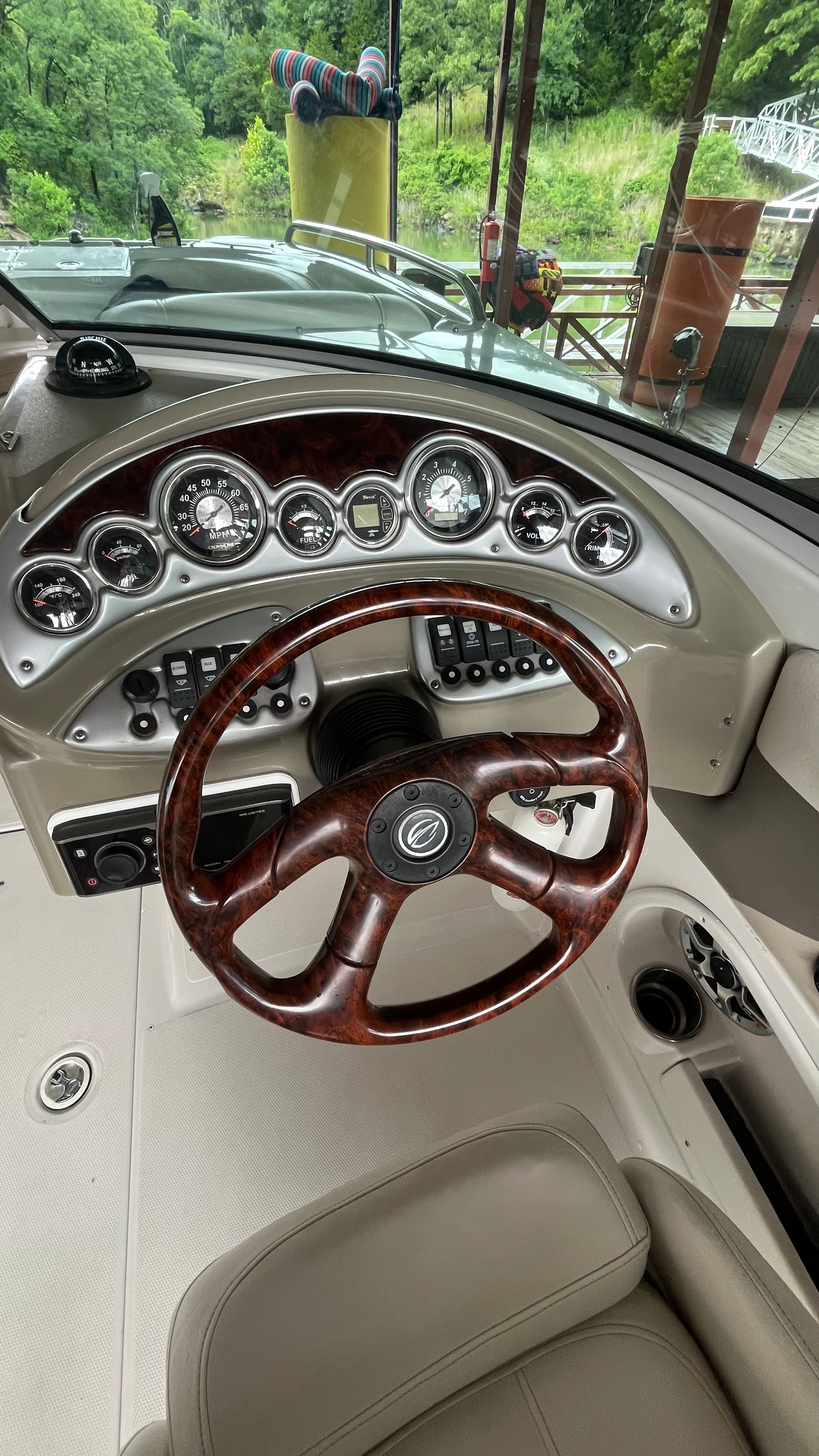The image shows the cockpit of a 2008 Crownline 252EX boat with a sleek wooden steering wheel.