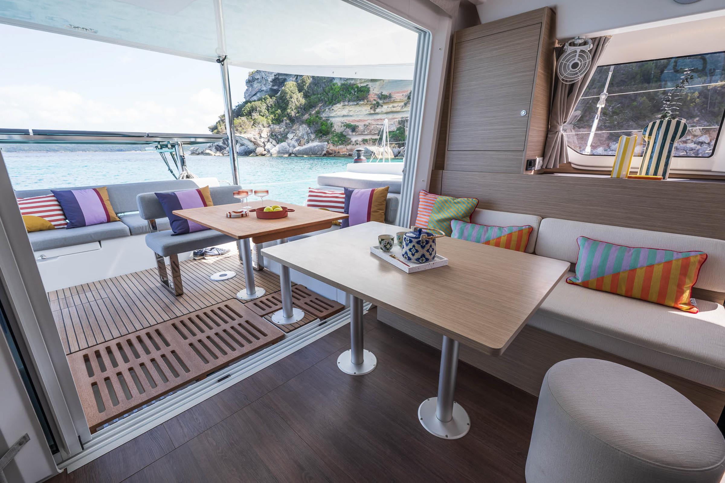 Luxurious interior of 2025 Lagoon 38 catamaran with colorful cushions and scenic ocean view.