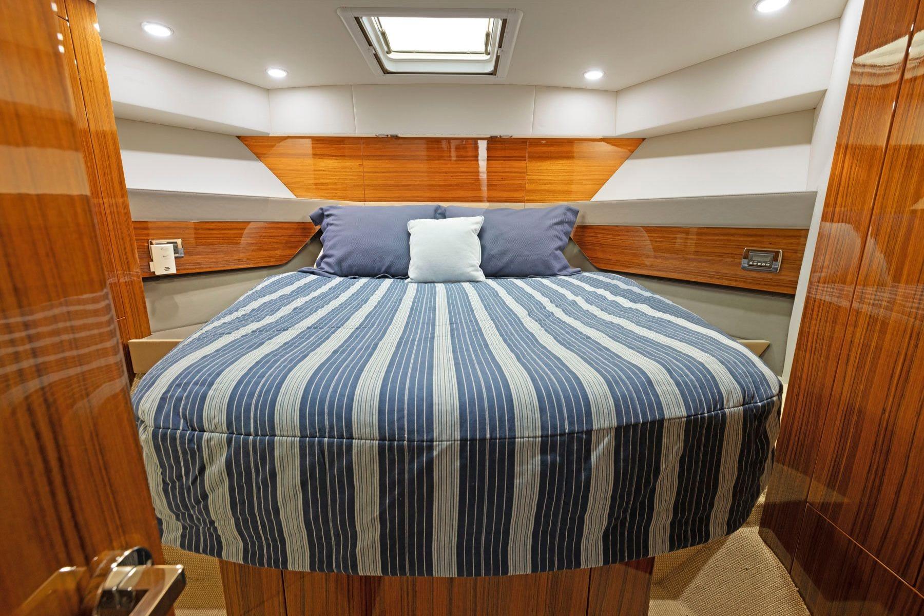 Luxurious cabin interior of 2014 Maritimo M50 yacht with striped bedding.