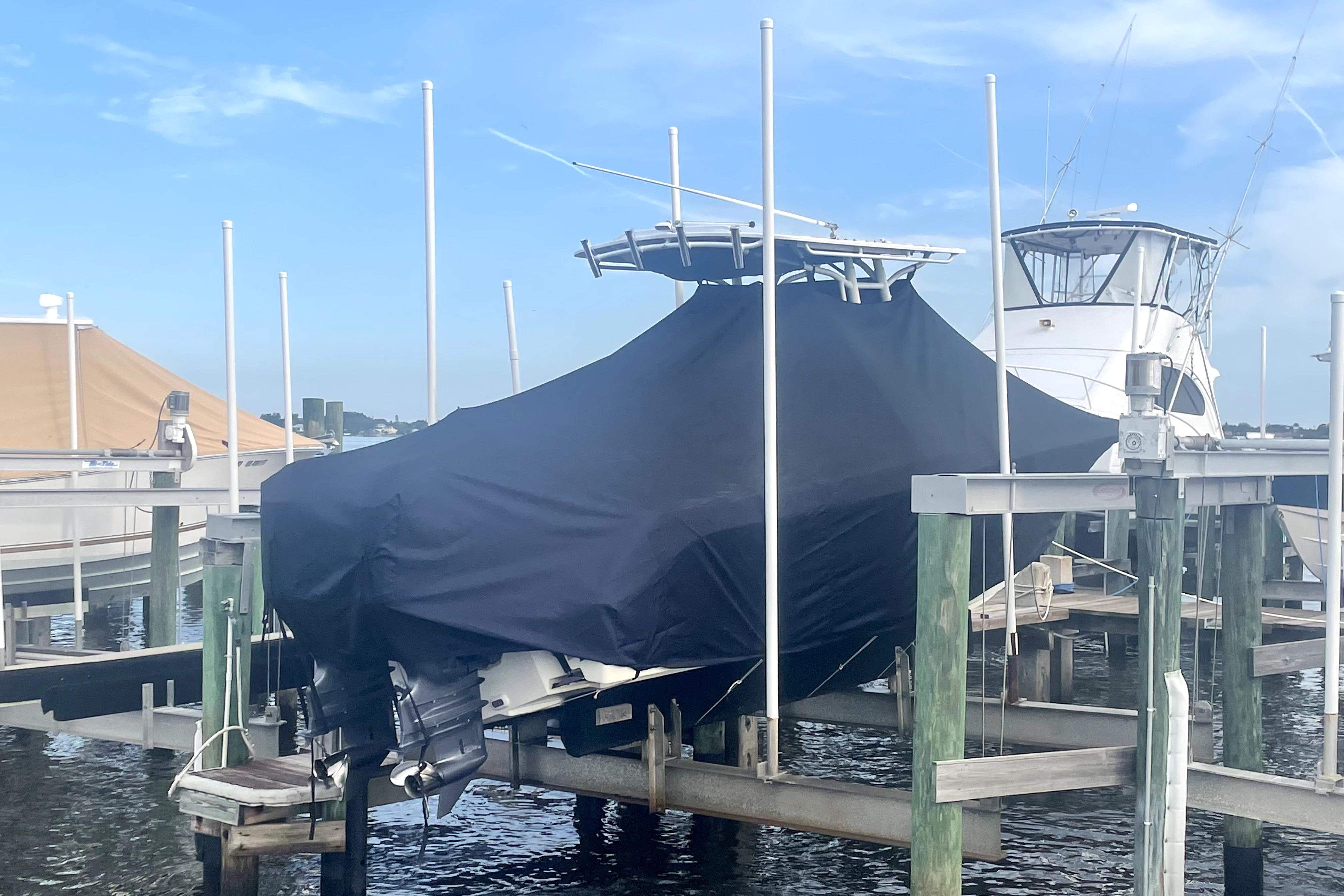 Covered 2015 Edgewater 245CC boat docked at marina under clear sky.