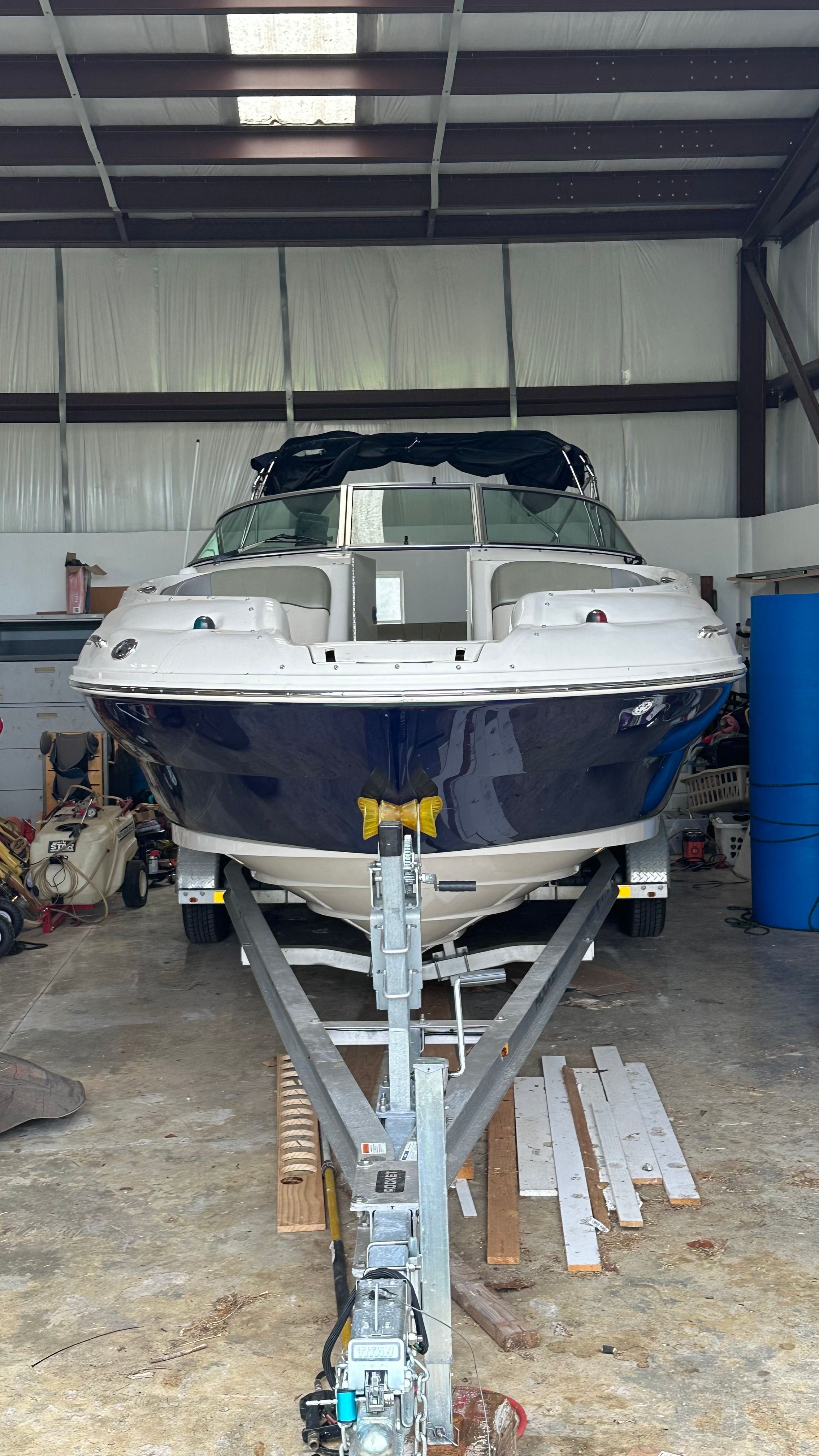A 2005 Sea Ray 240 Sundeck is in a warehouse on a trailer.
