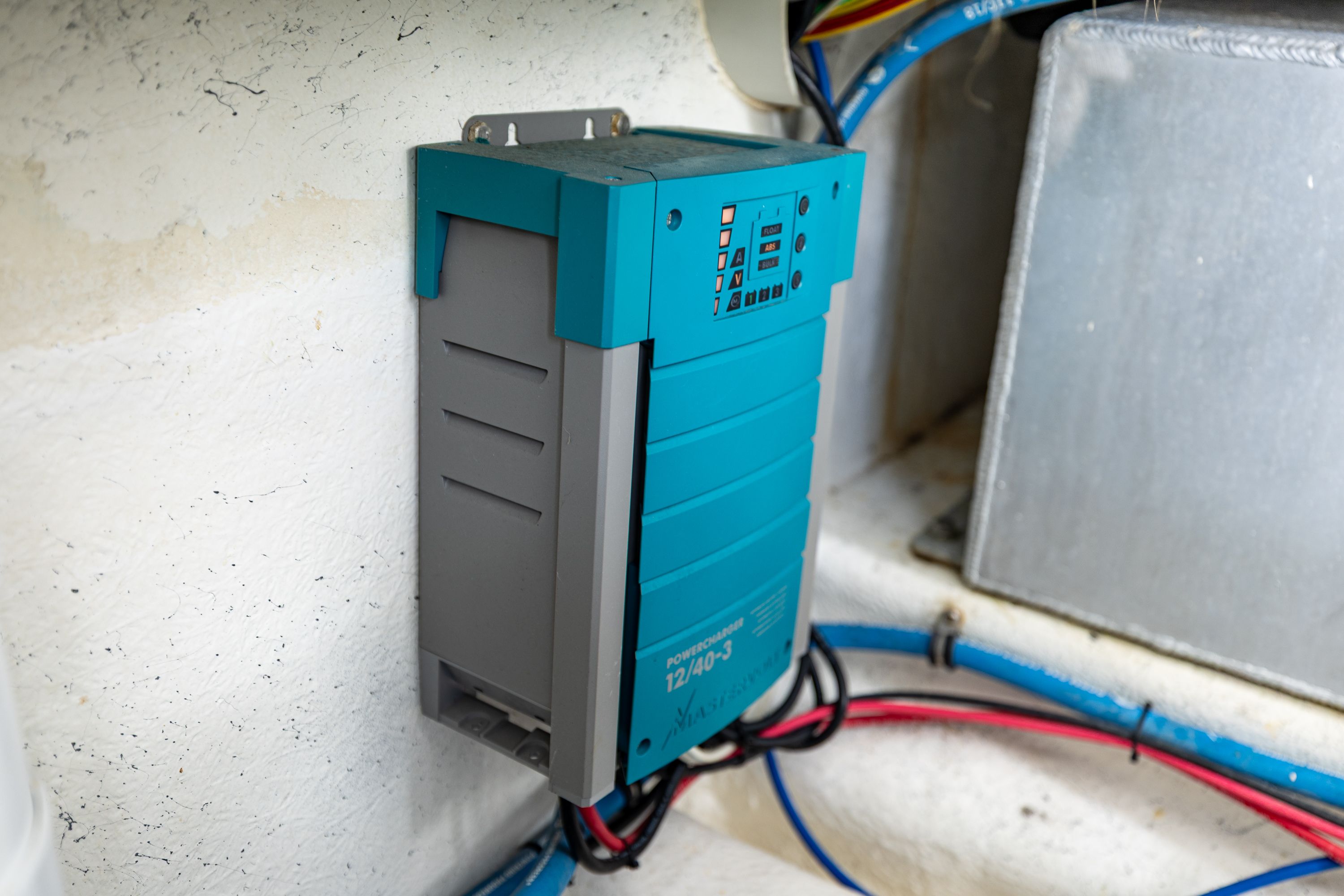 An electrical device is mounted on a boat wall, surrounded by cables.
