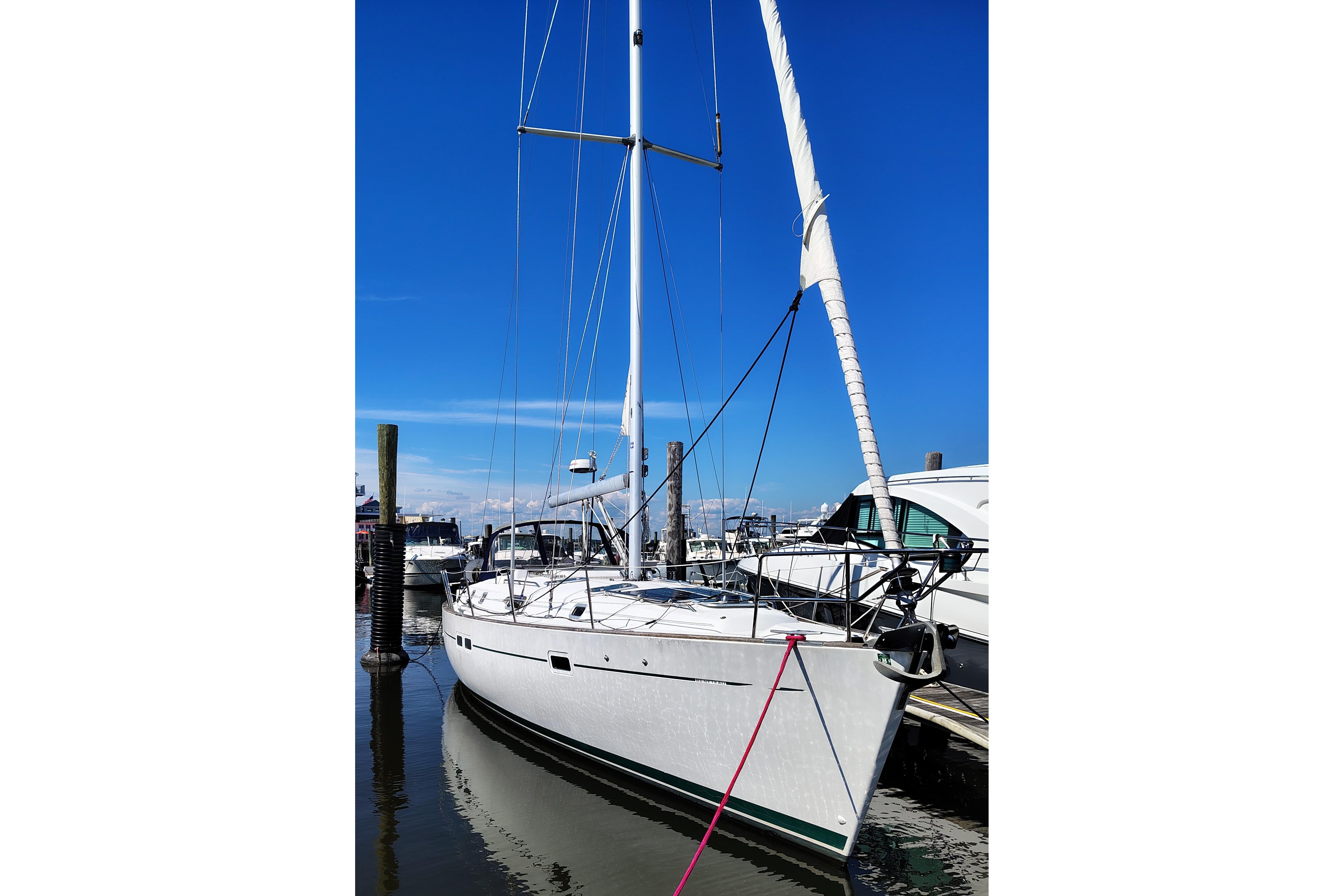 Sailboat Beneteau Oceanis 411, 2001 model, docked at marina under clear blue sky.