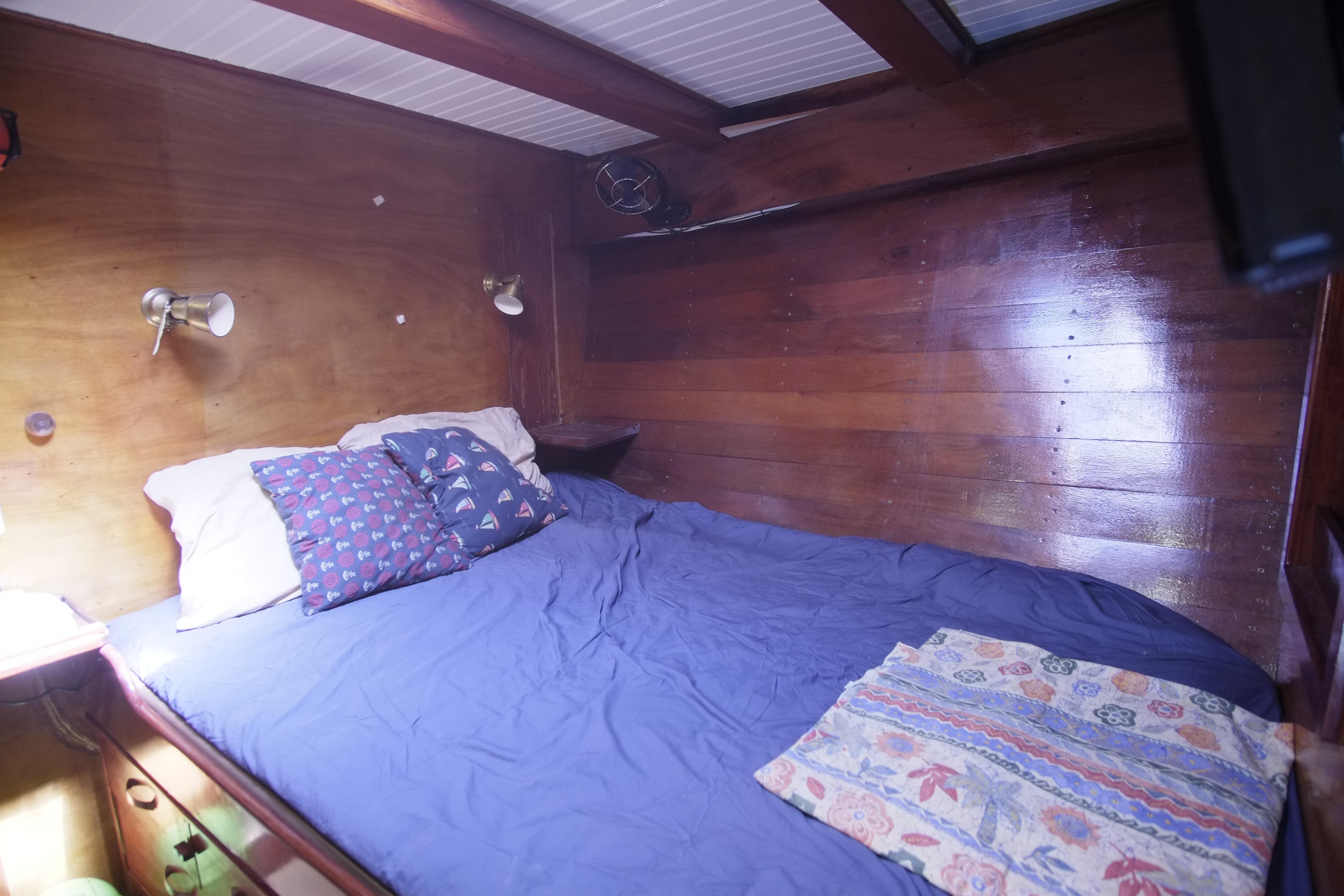 Cozy cabin bedroom in 2006 Custom Bud Macintosh schooner with wooden walls and blue bedding.
