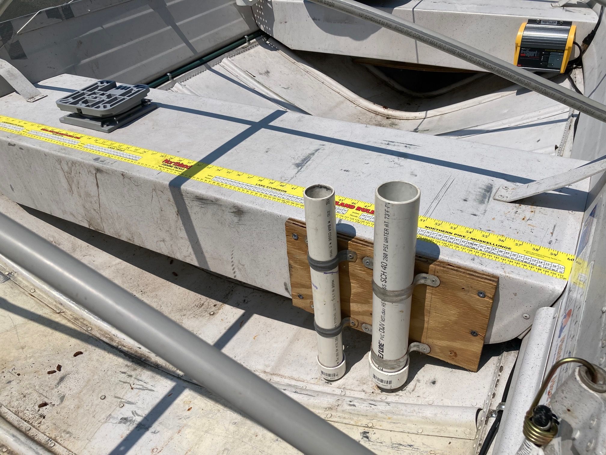 The boat has a white surface with yellow measuring tape and PVC pipes.