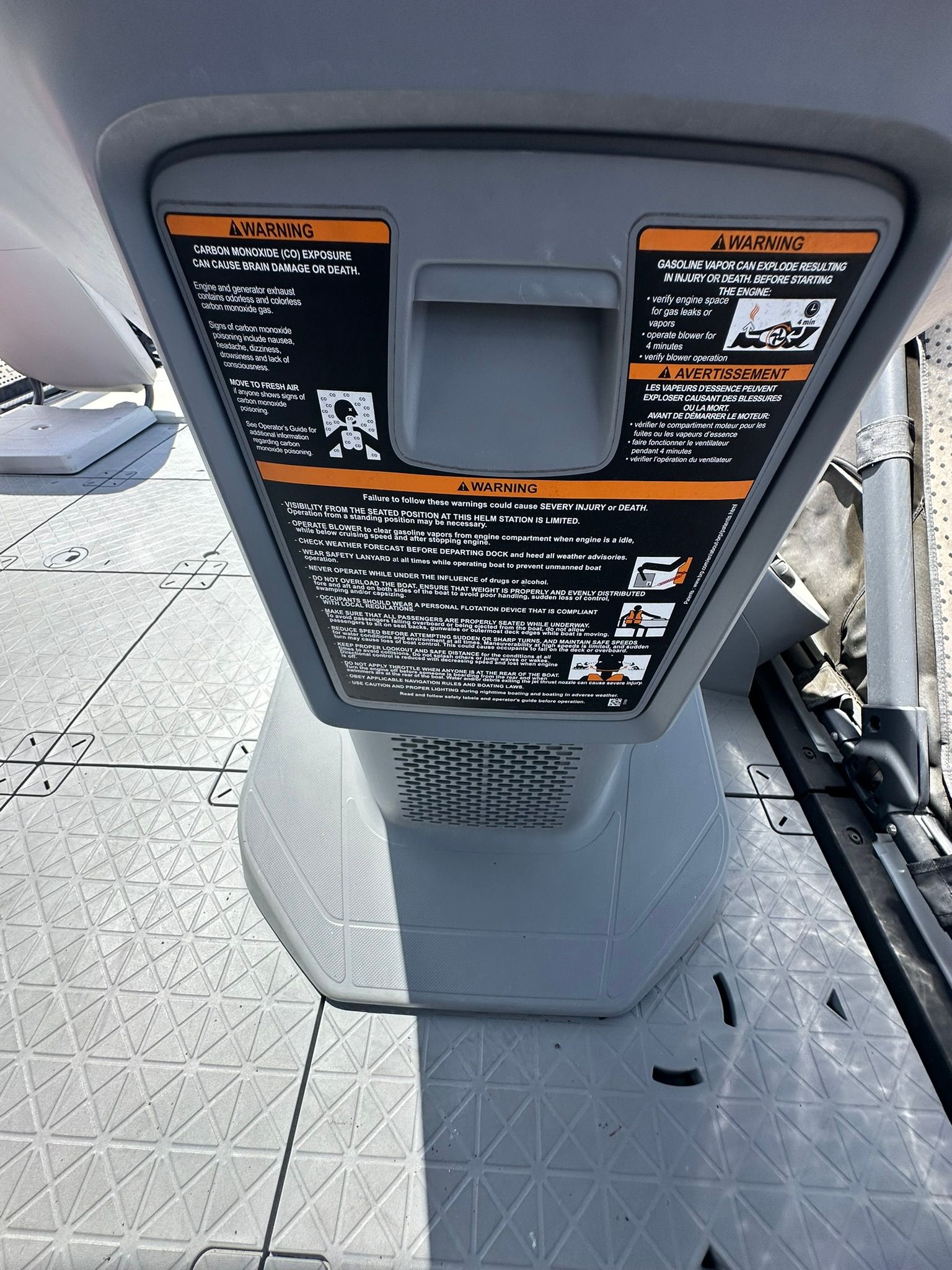 Close-up of a gray boat part with warning labels.