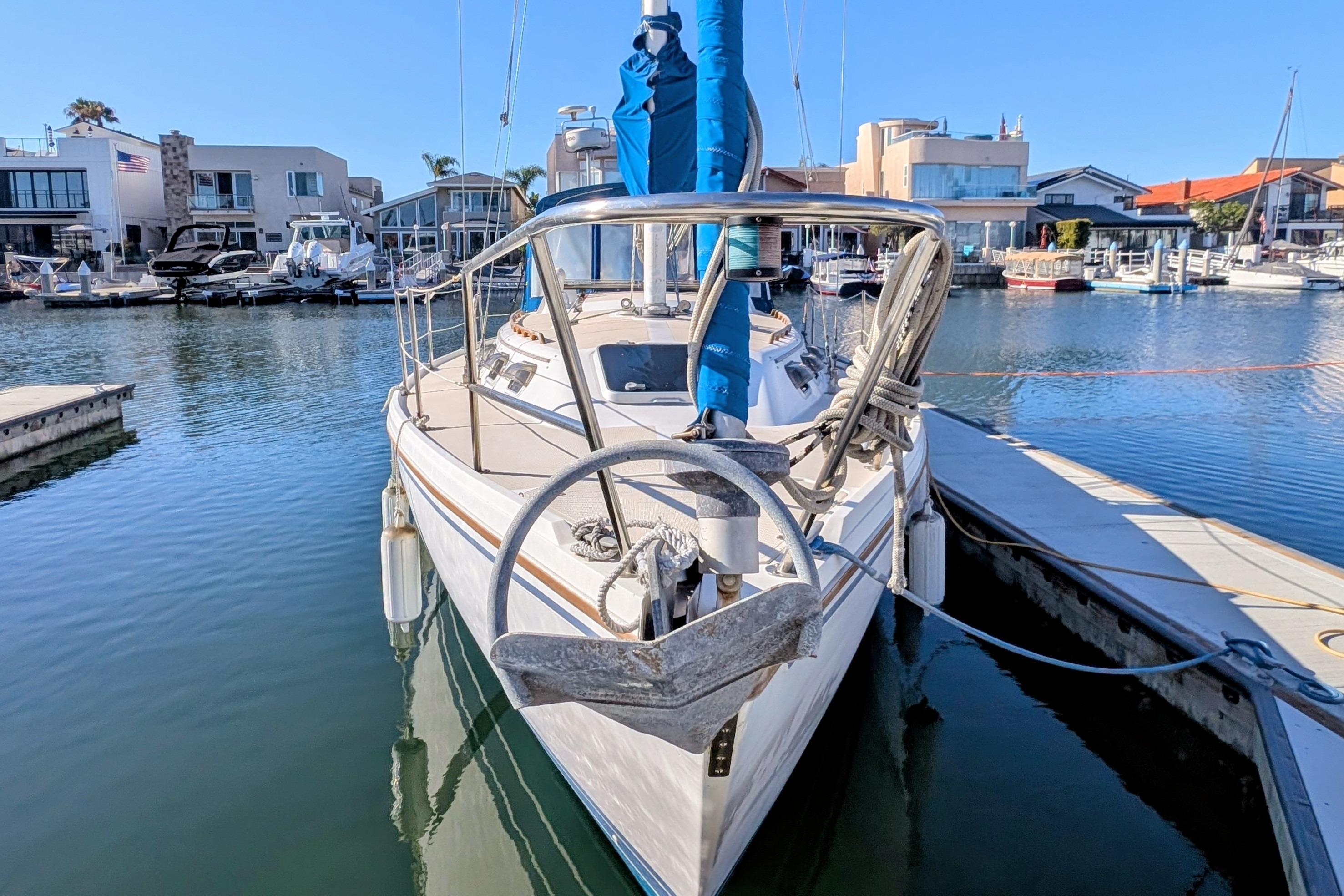 1989 Catalina 34 sailboat docked in a marina, surrounded by waterfront homes.