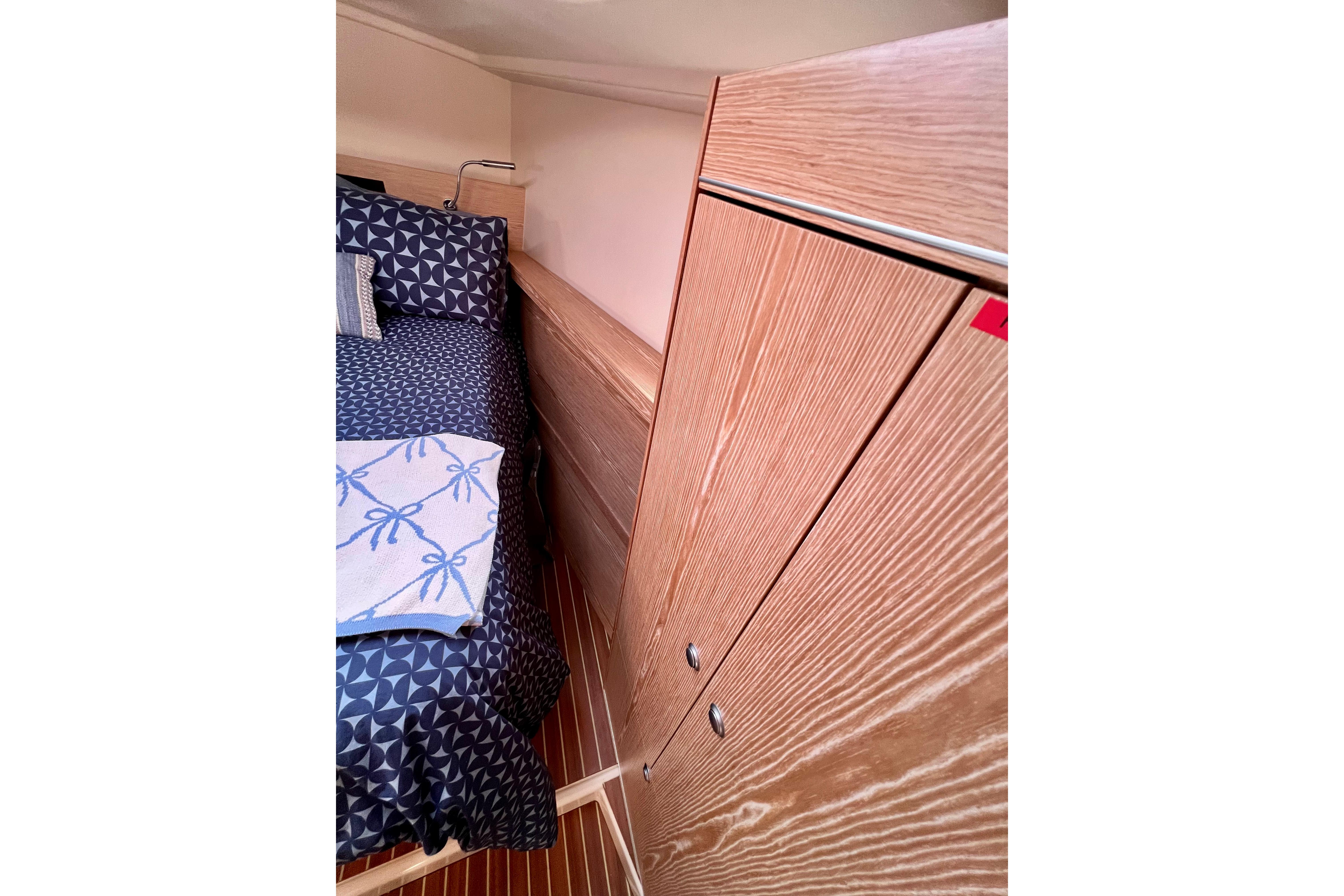 Cozy cabin interior of 2016 Hanse 455 yacht with wooden cabinetry and patterned bedding.